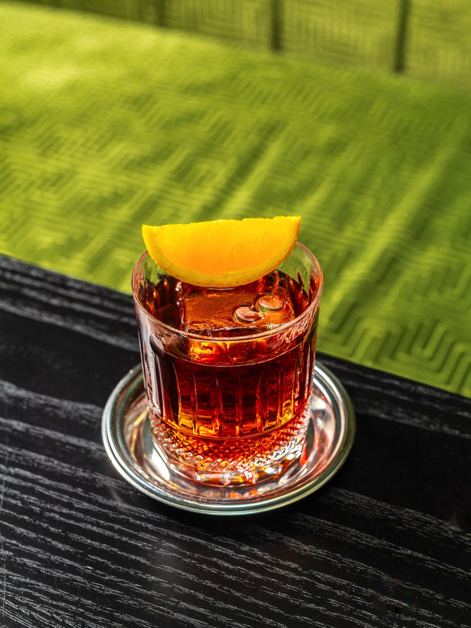 a glass of alcohol with a slice of orange on a table