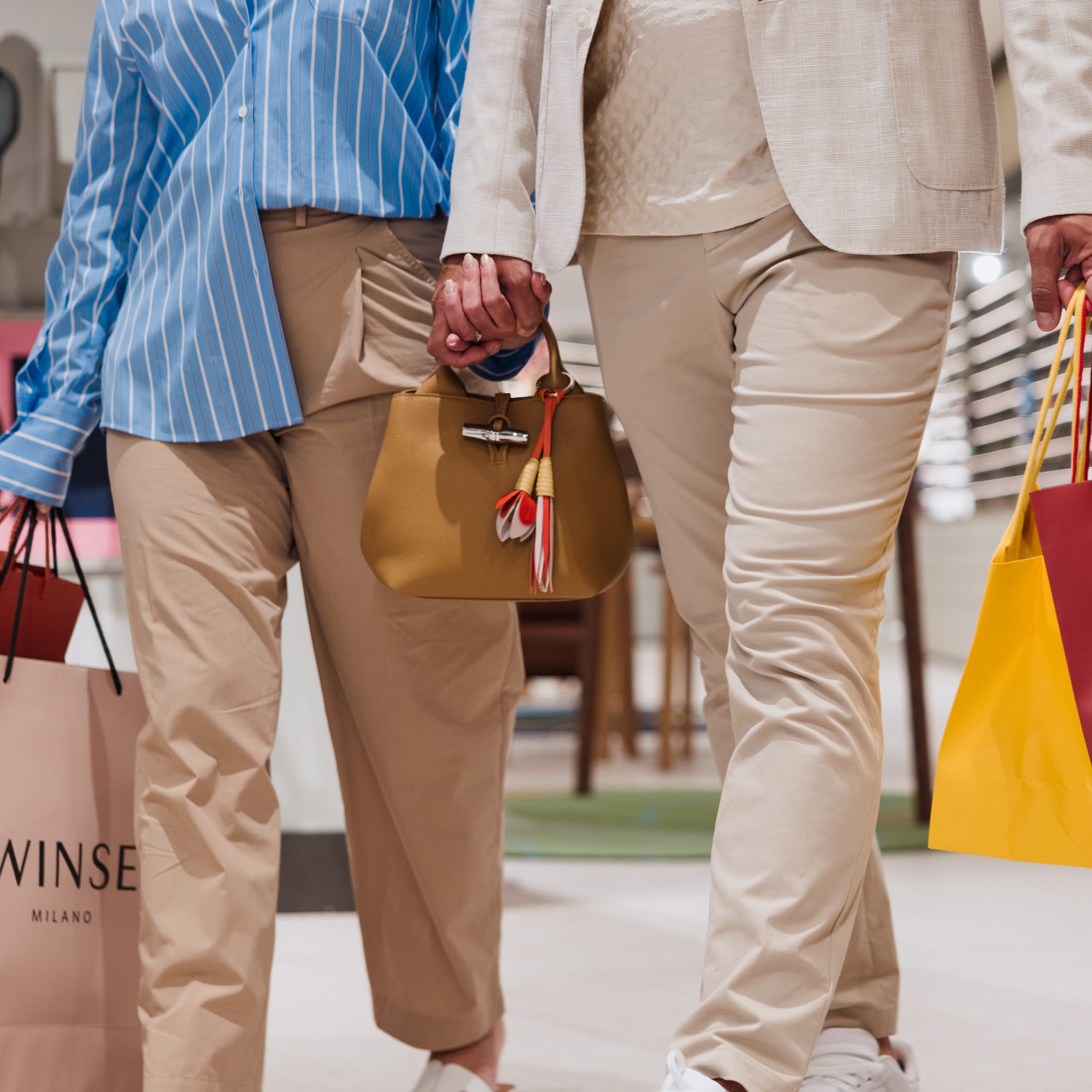 Shoppers holding hands, carrying multiple shopping bags, including Twinse Milano.