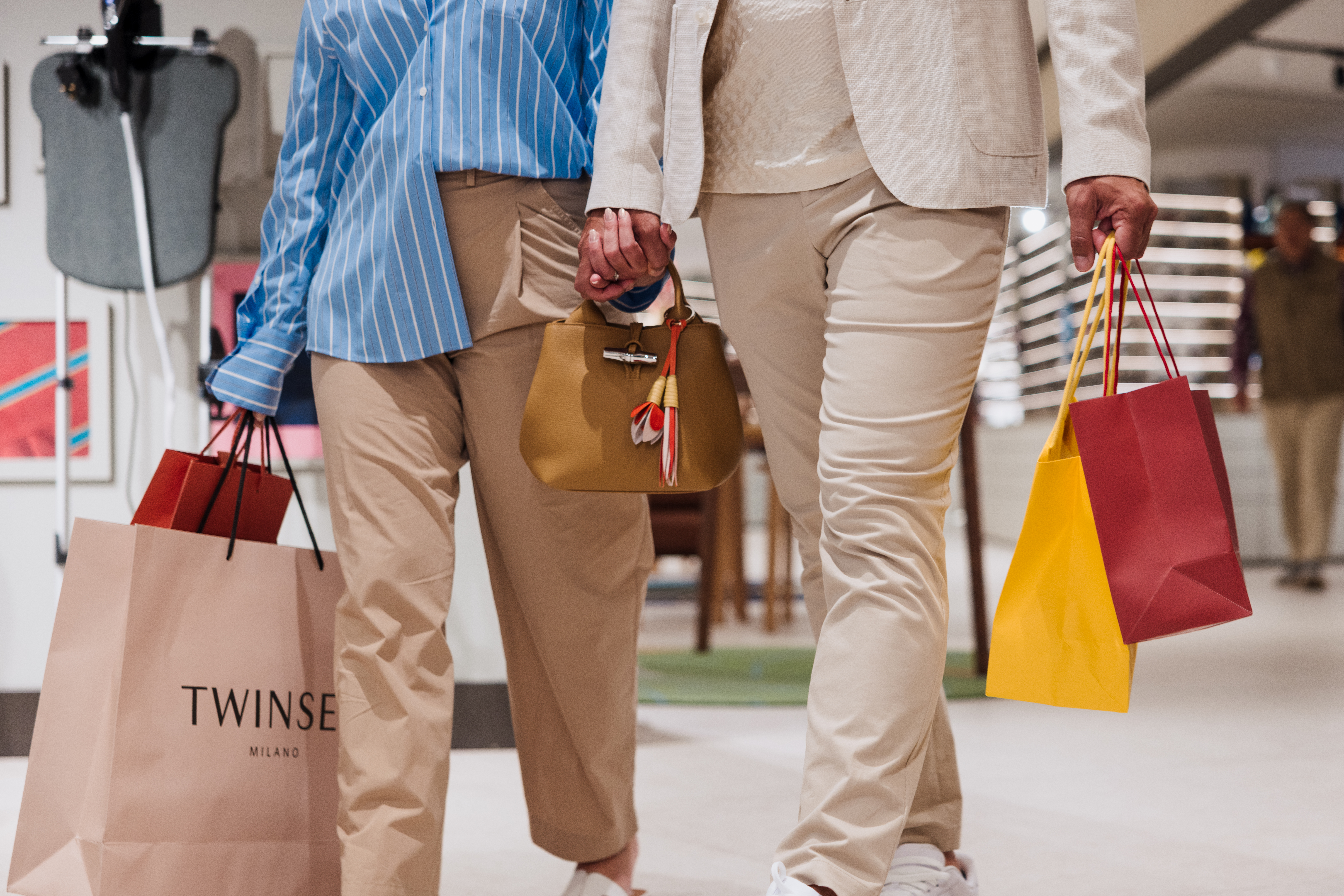 Shoppers holding hands, carrying multiple shopping bags, including Twinse Milano.