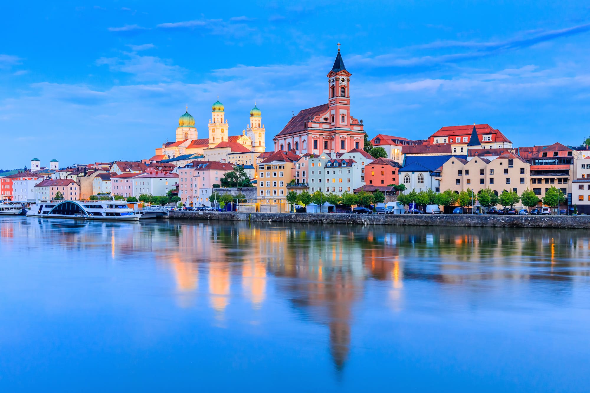 Passau, Alemania: edificios coloridos, catedral y río Danubio al atardecer.