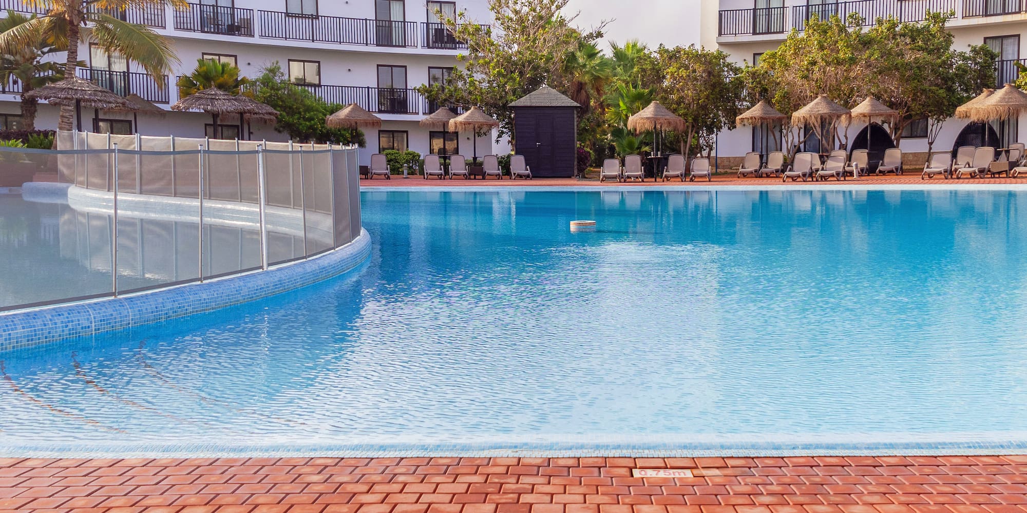 a pool with a fence and a building in the background