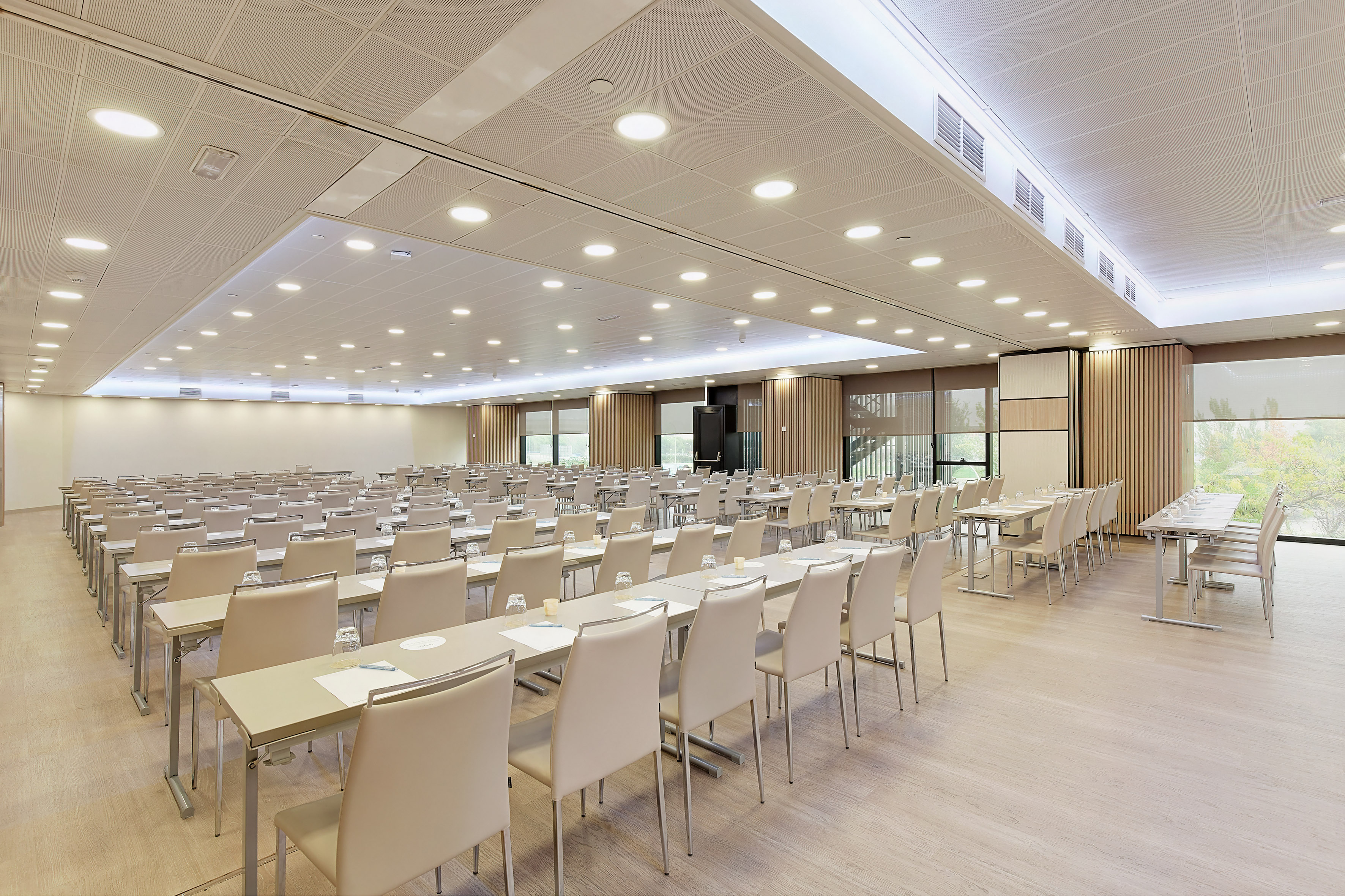Bright modern conference room with light tables, chairs, and wood-look floor.
