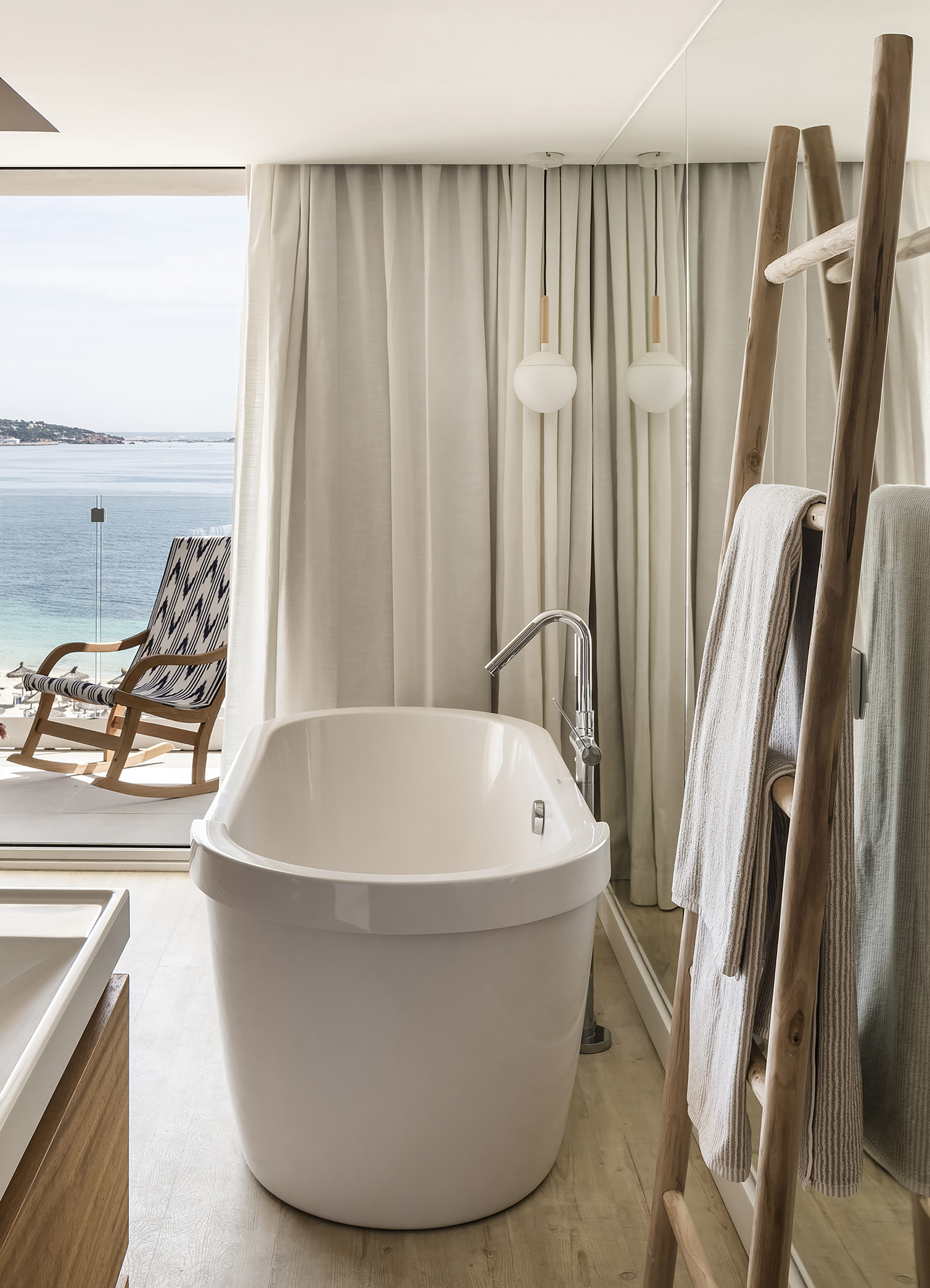 Modern bathroom with white freestanding tub and sea view balcony