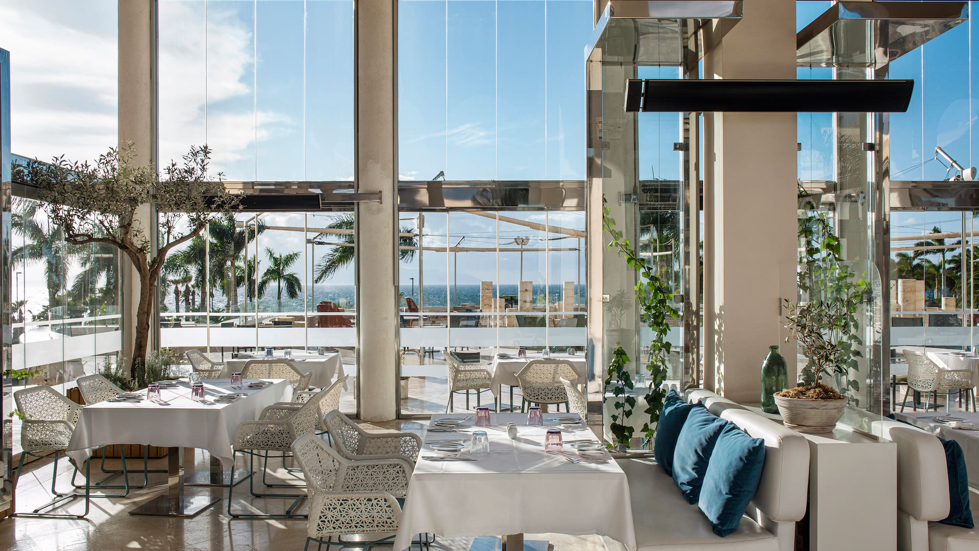 a room with white tables and chairs and a large window