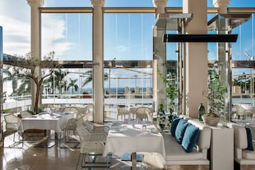 a room with white tables and chairs and a large window