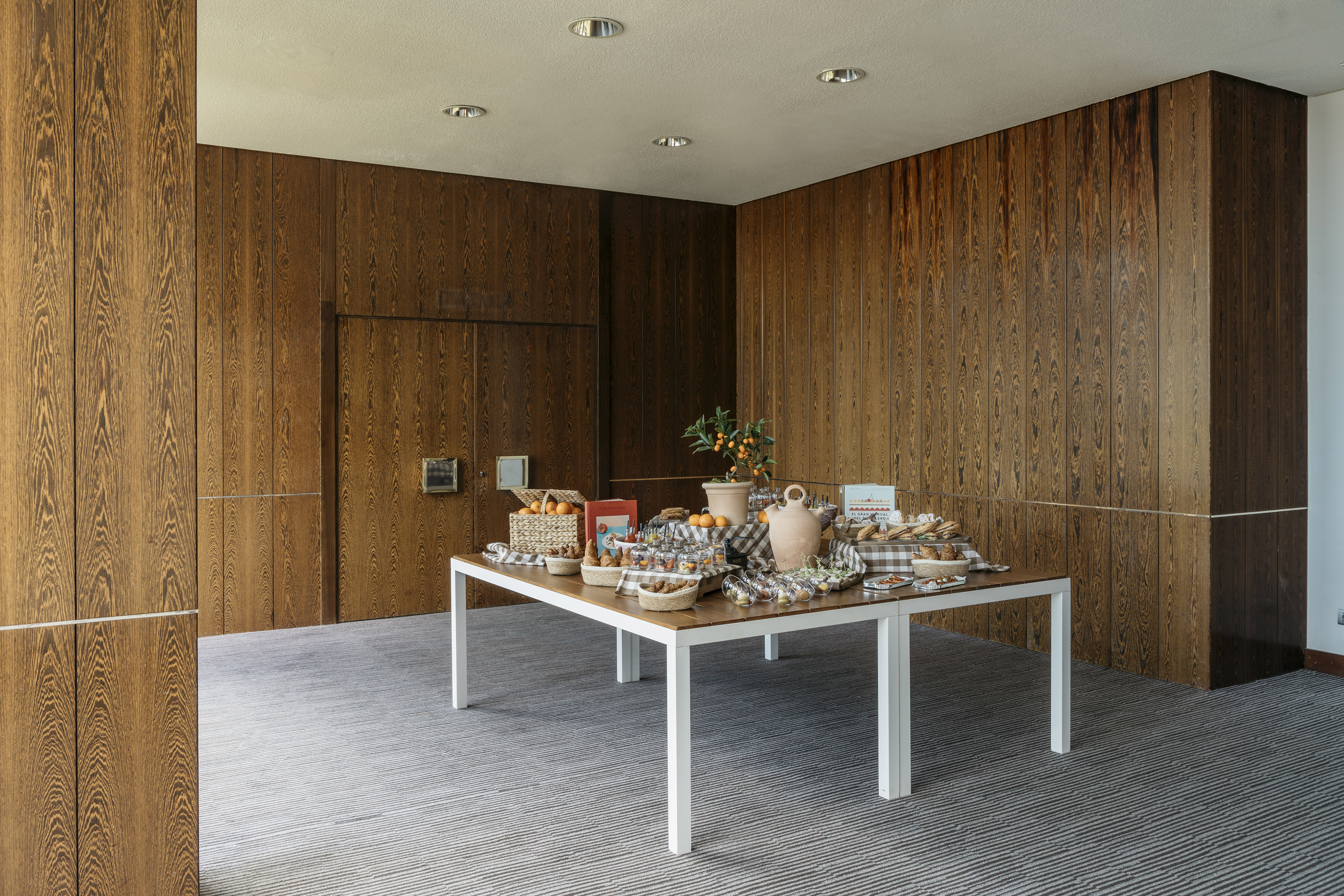 Modern wood-paneled room with a breakfast buffet on a striped carpet.