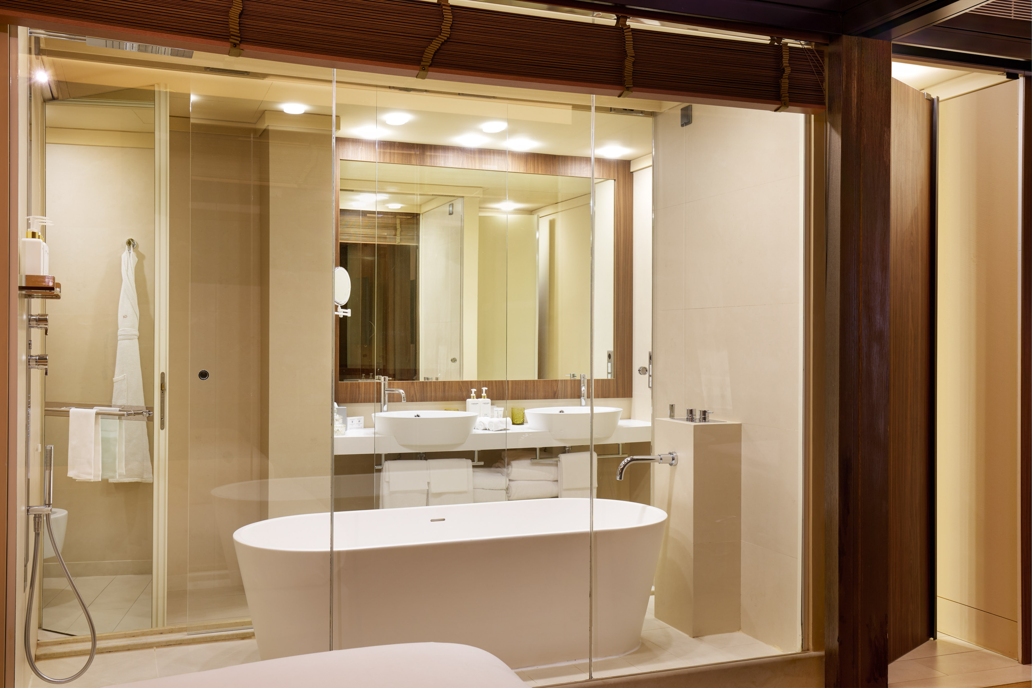 Luxury hotel bathroom with freestanding tub, glass shower, and dual sinks.