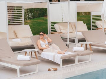 a woman sitting in a lounge chair by a pool