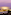 Illuminated coastal resort at twilight with palm trees and ocean view.