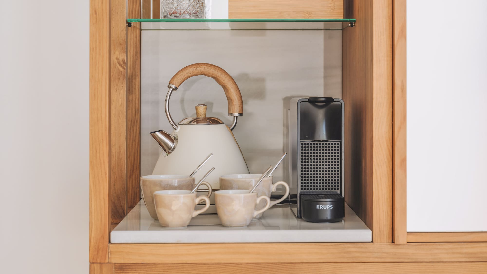 Hotel coffee and tea station with kettle, Krups machine, ceramic mugs.