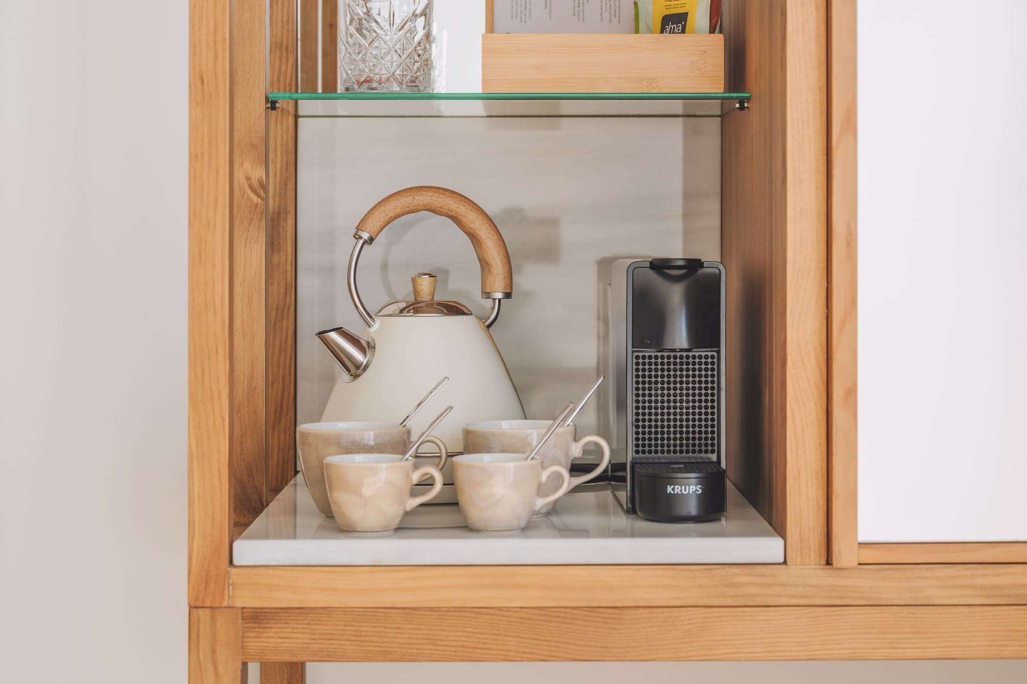 Hotel coffee and tea station with kettle, Krups machine, ceramic mugs.