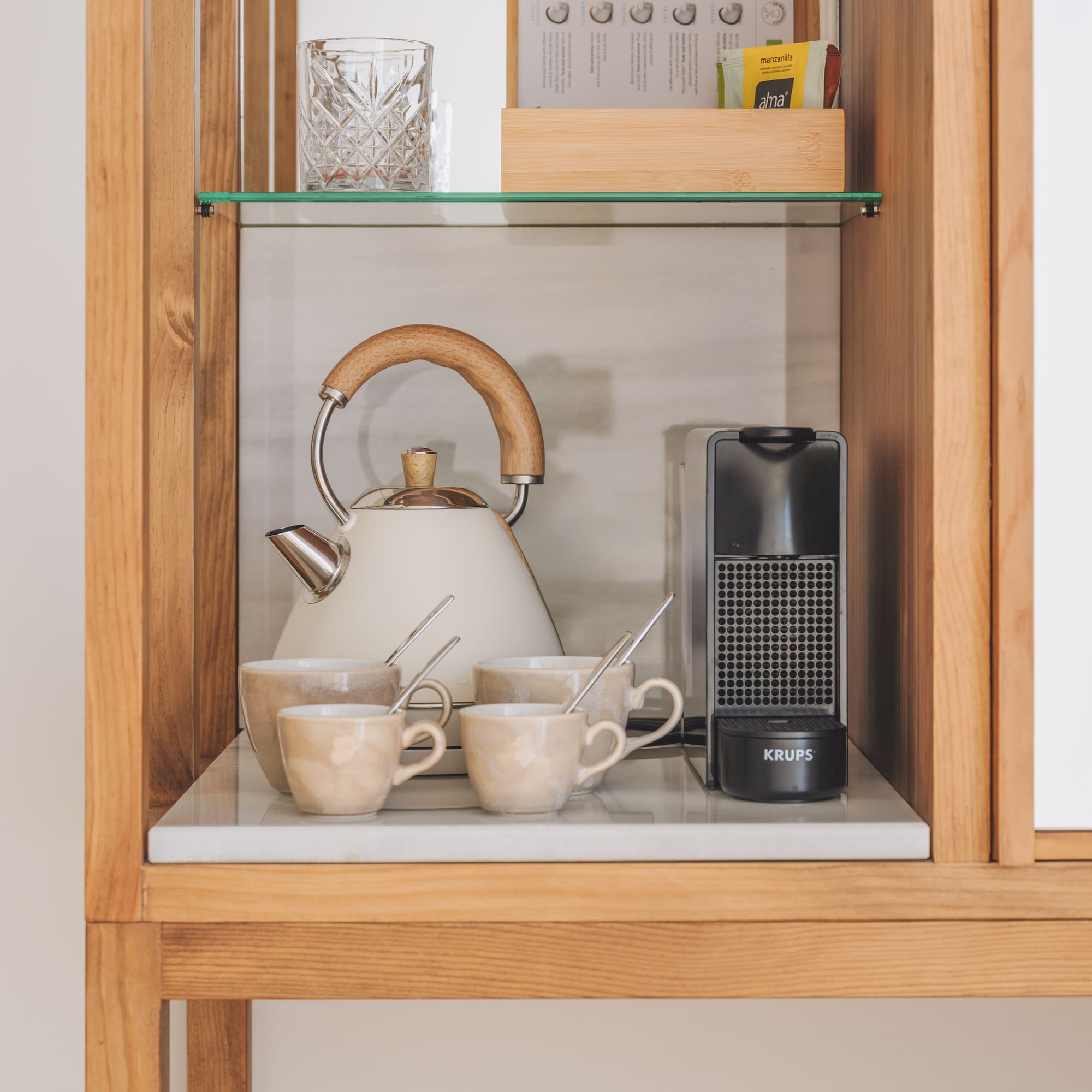 Hotel coffee and tea station with kettle, Krups machine, ceramic mugs.