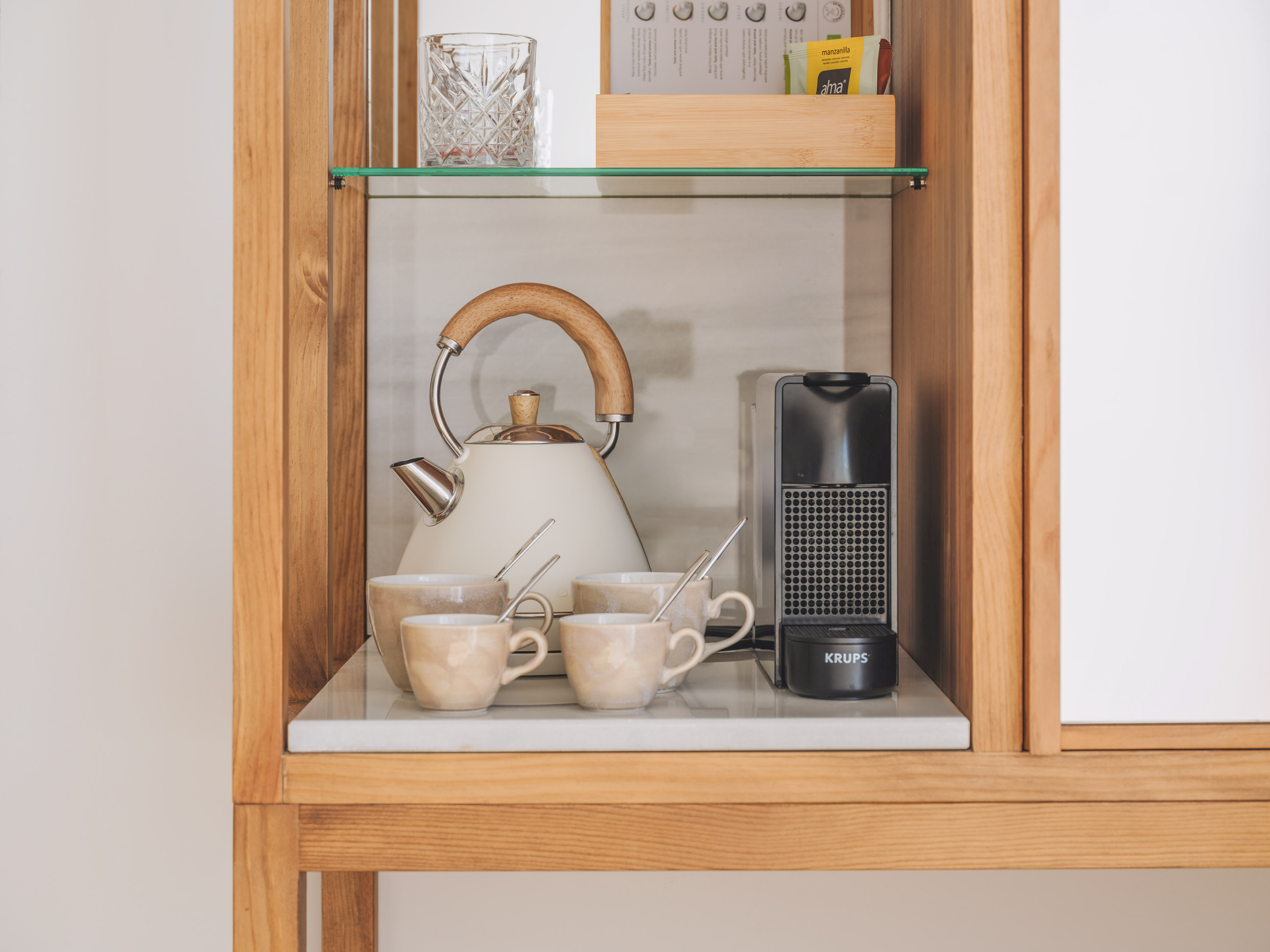 Hotel coffee and tea station with kettle, Krups machine, ceramic mugs.