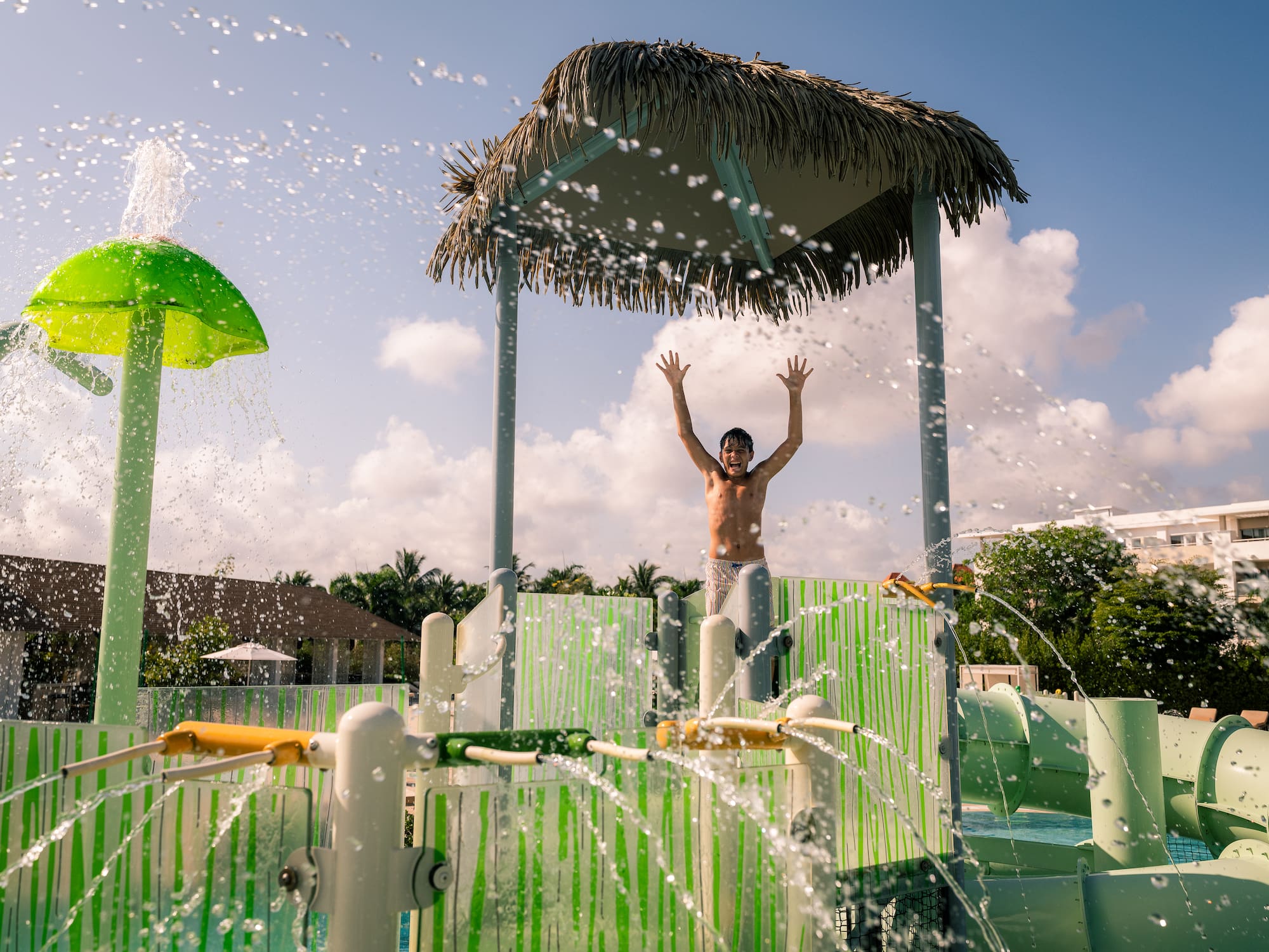 a man standing in a water park with his arms up