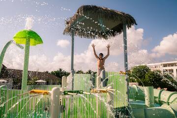 a man standing in a water park with his arms up