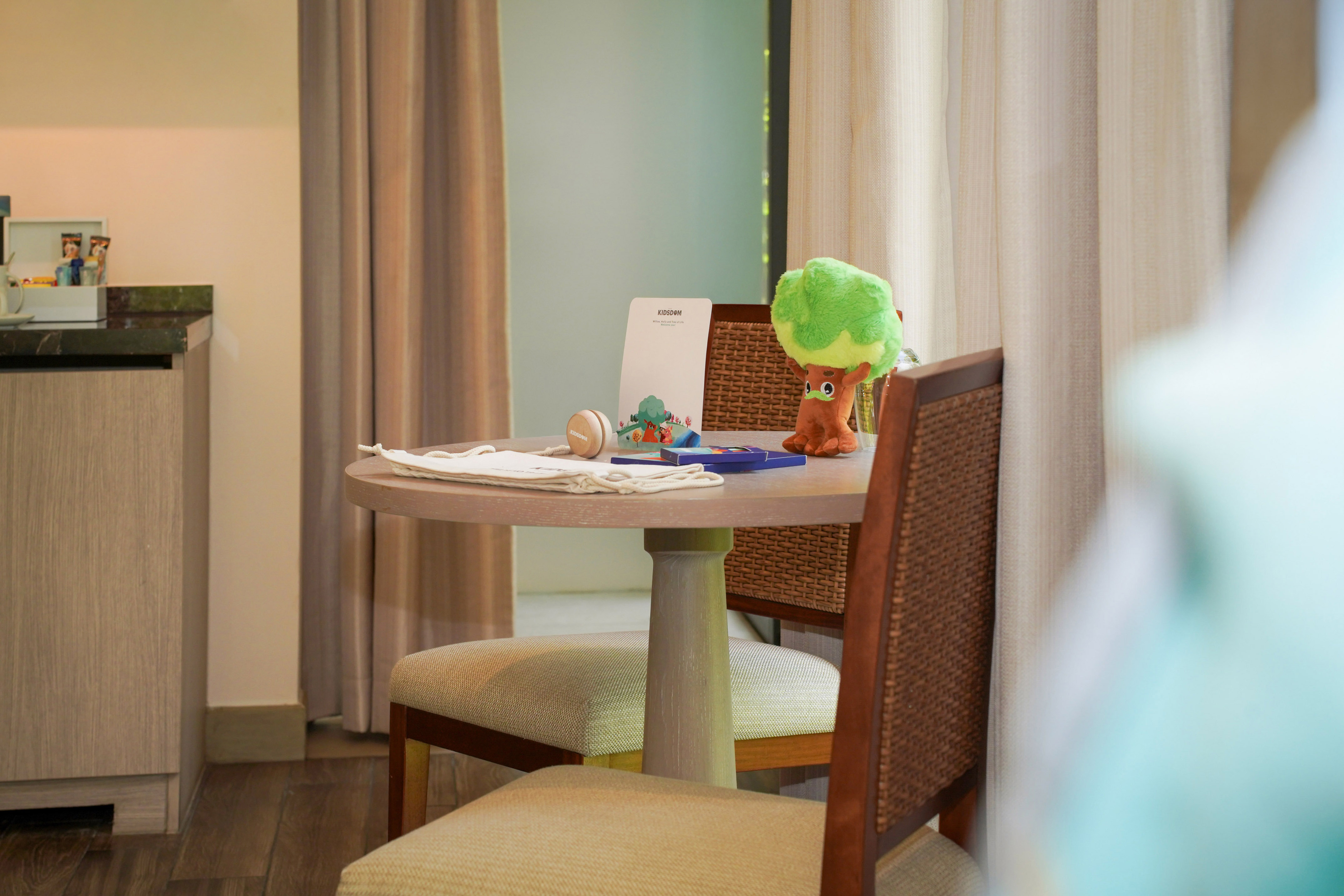 Hotel room kids' table with tree plush, Kidsdom activity card, and yoyo.