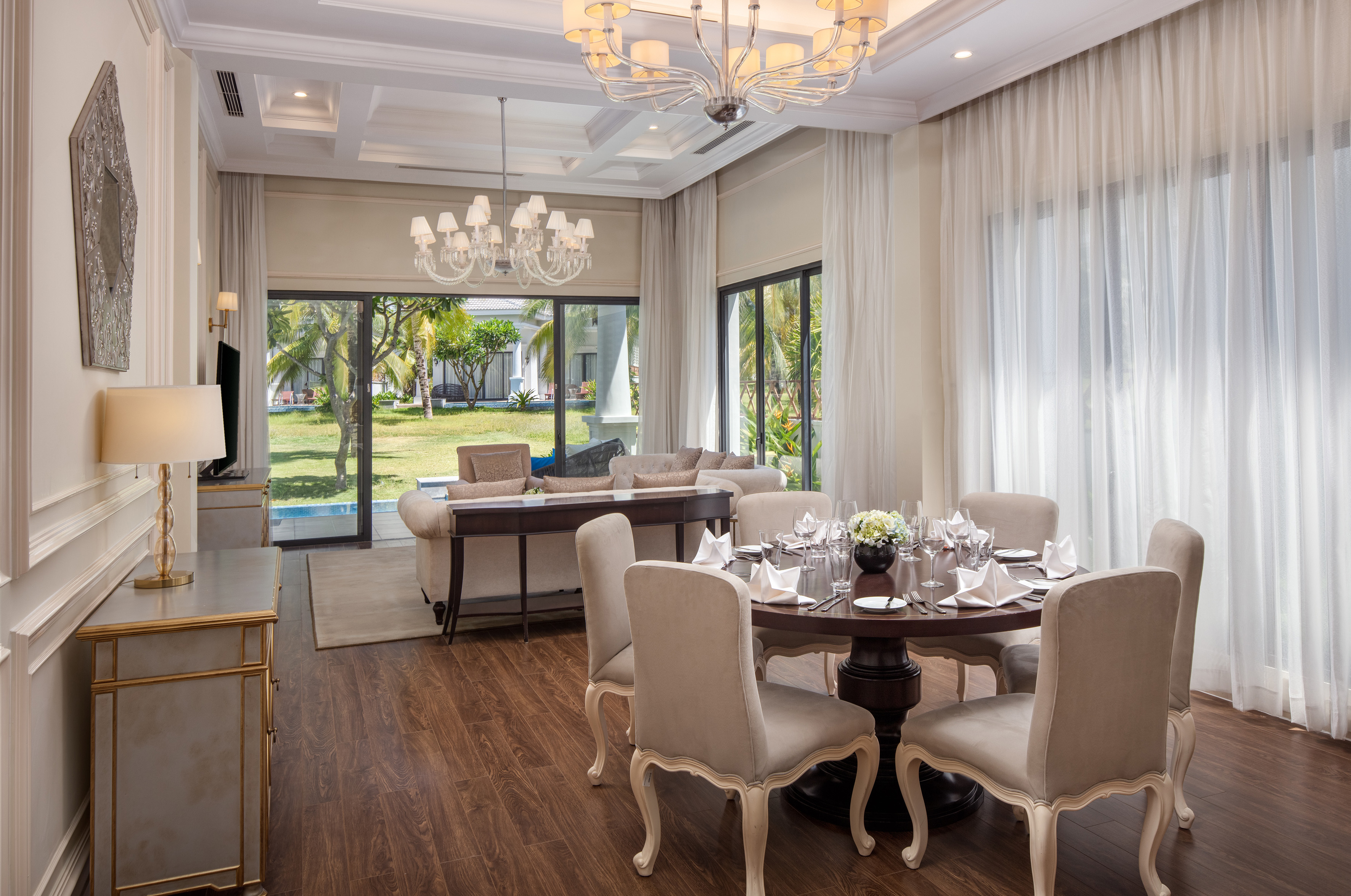 Luxury living and dining room with elegant decor and tropical garden view.