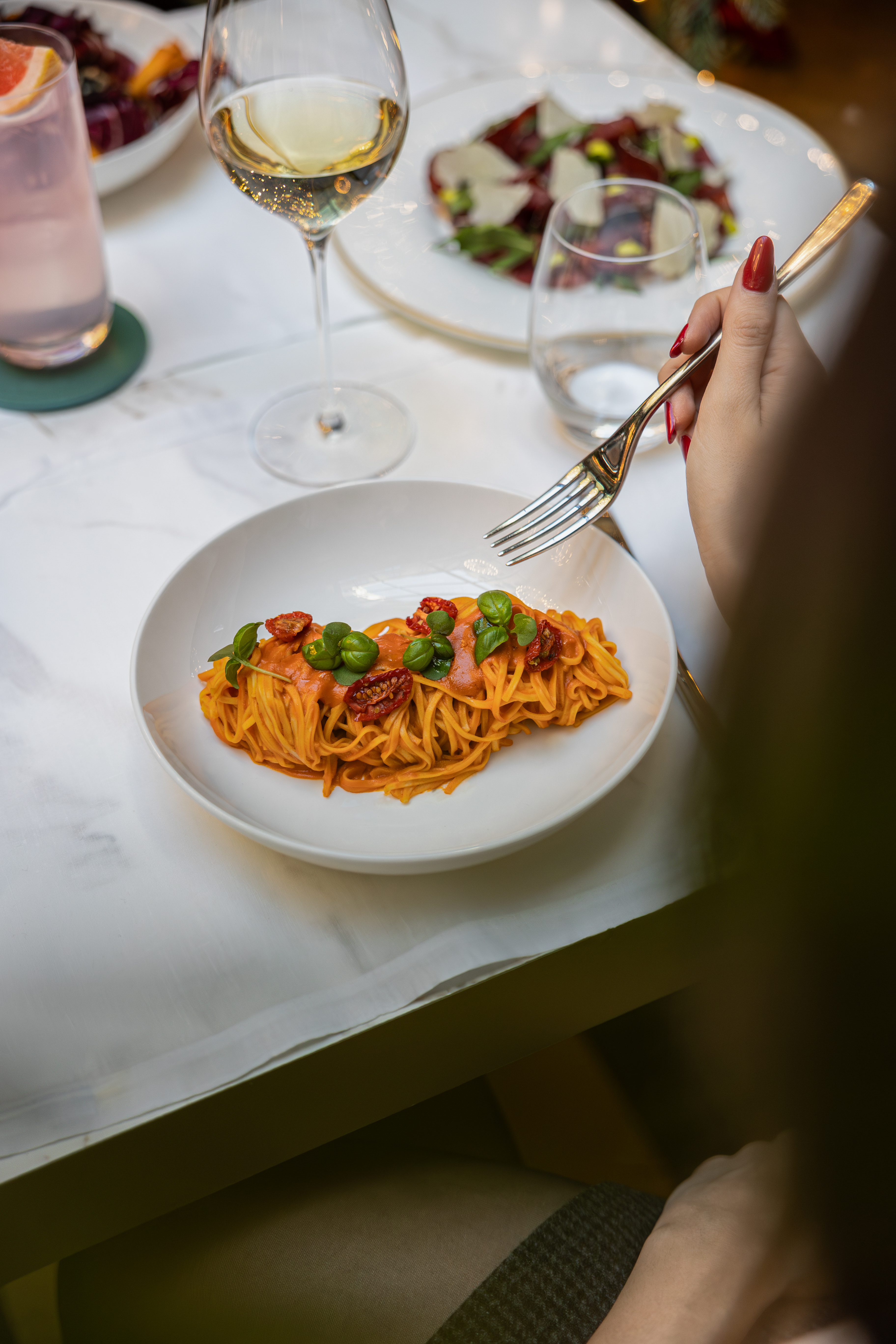 Pasta with red sauce, sun-dried tomatoes, basil. Hand with fork.