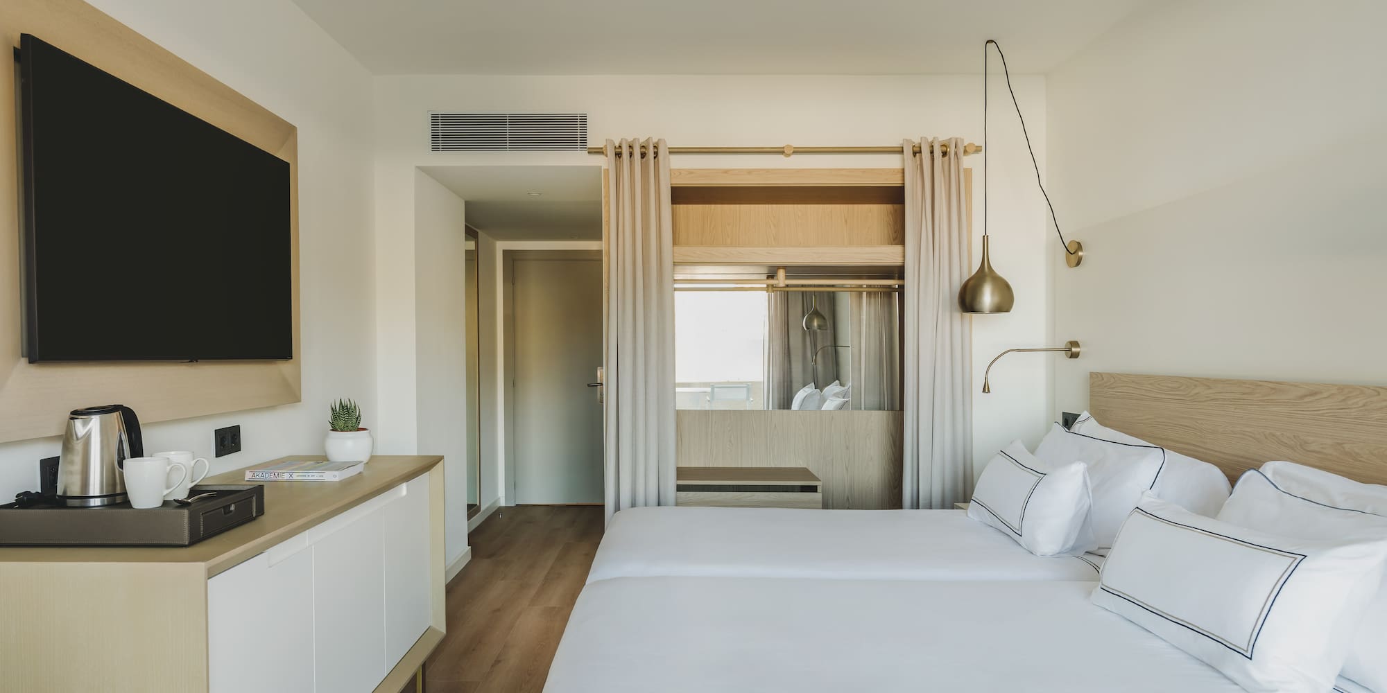Moderna habitación de hotel con dos camas individuales y TV.