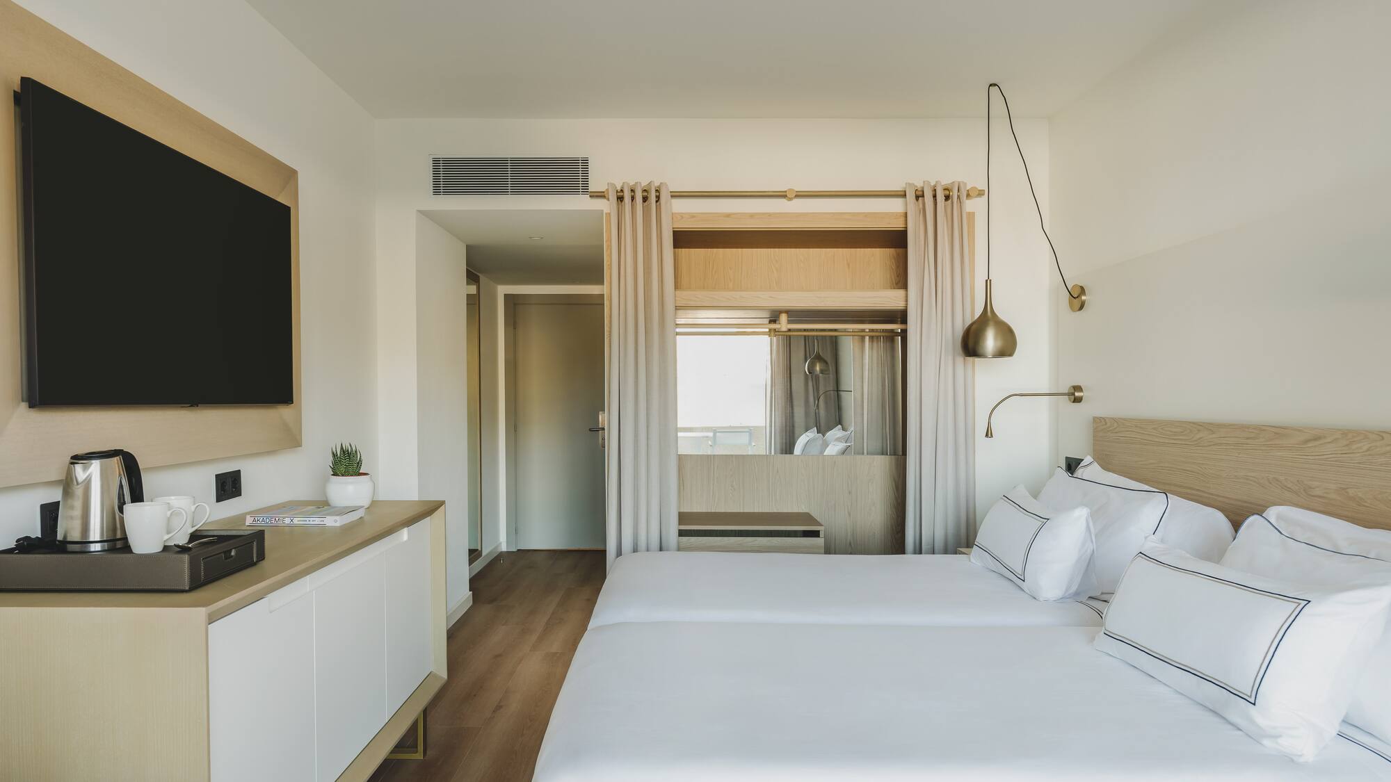 Moderna habitación de hotel con dos camas individuales y TV.