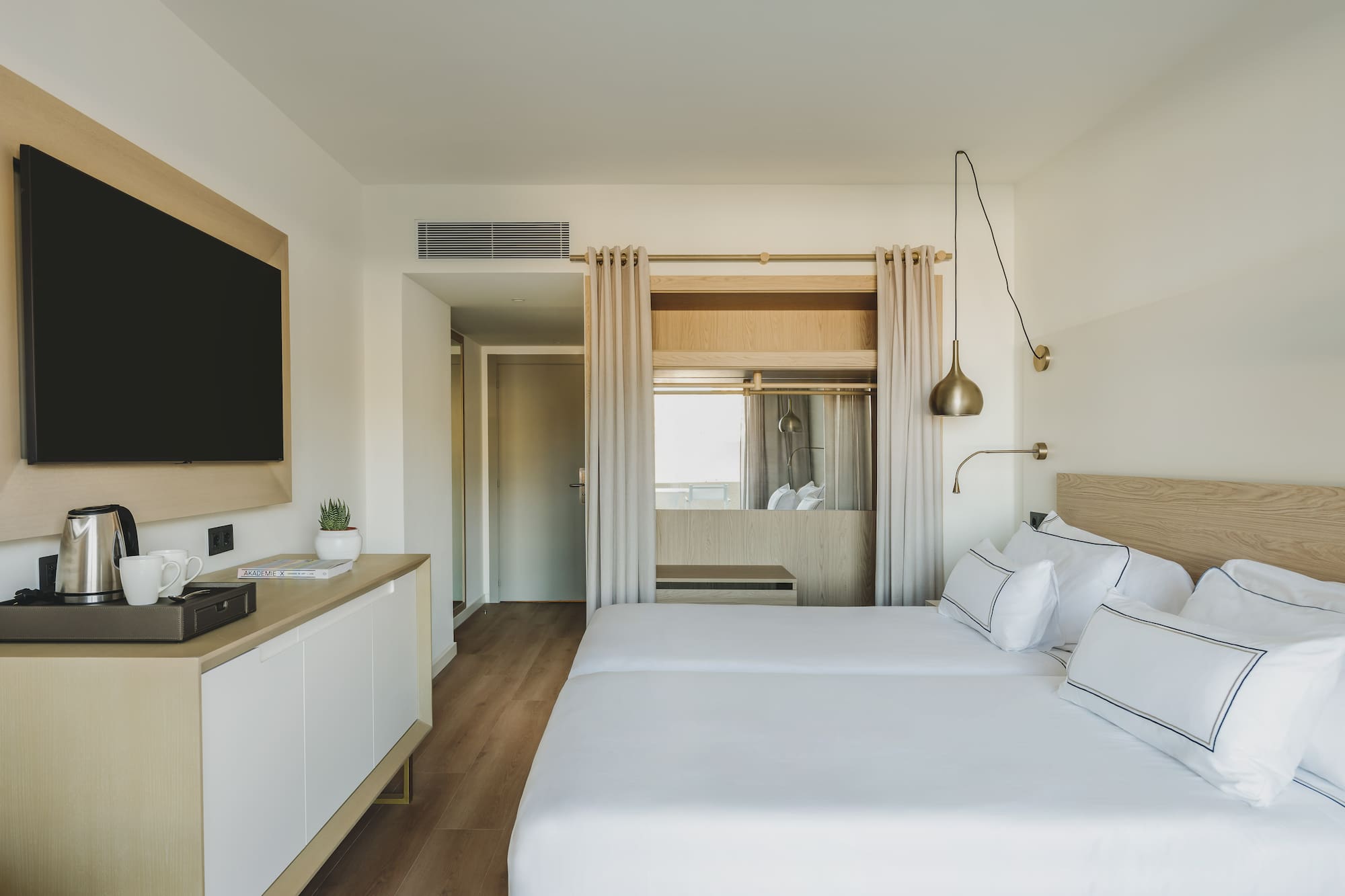 Moderna habitación de hotel con dos camas individuales y TV.