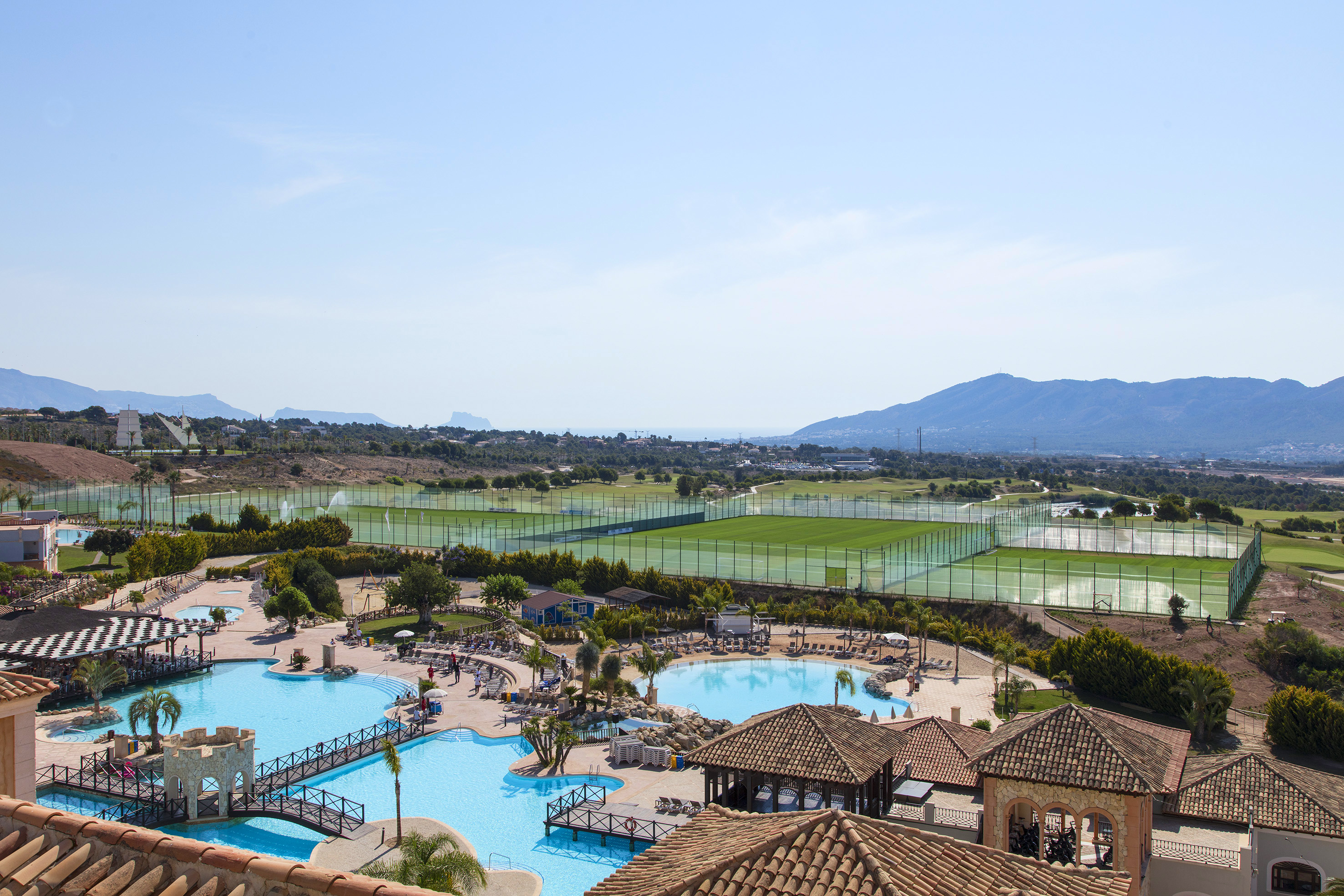 a swimming pool with a tennis court and a large building