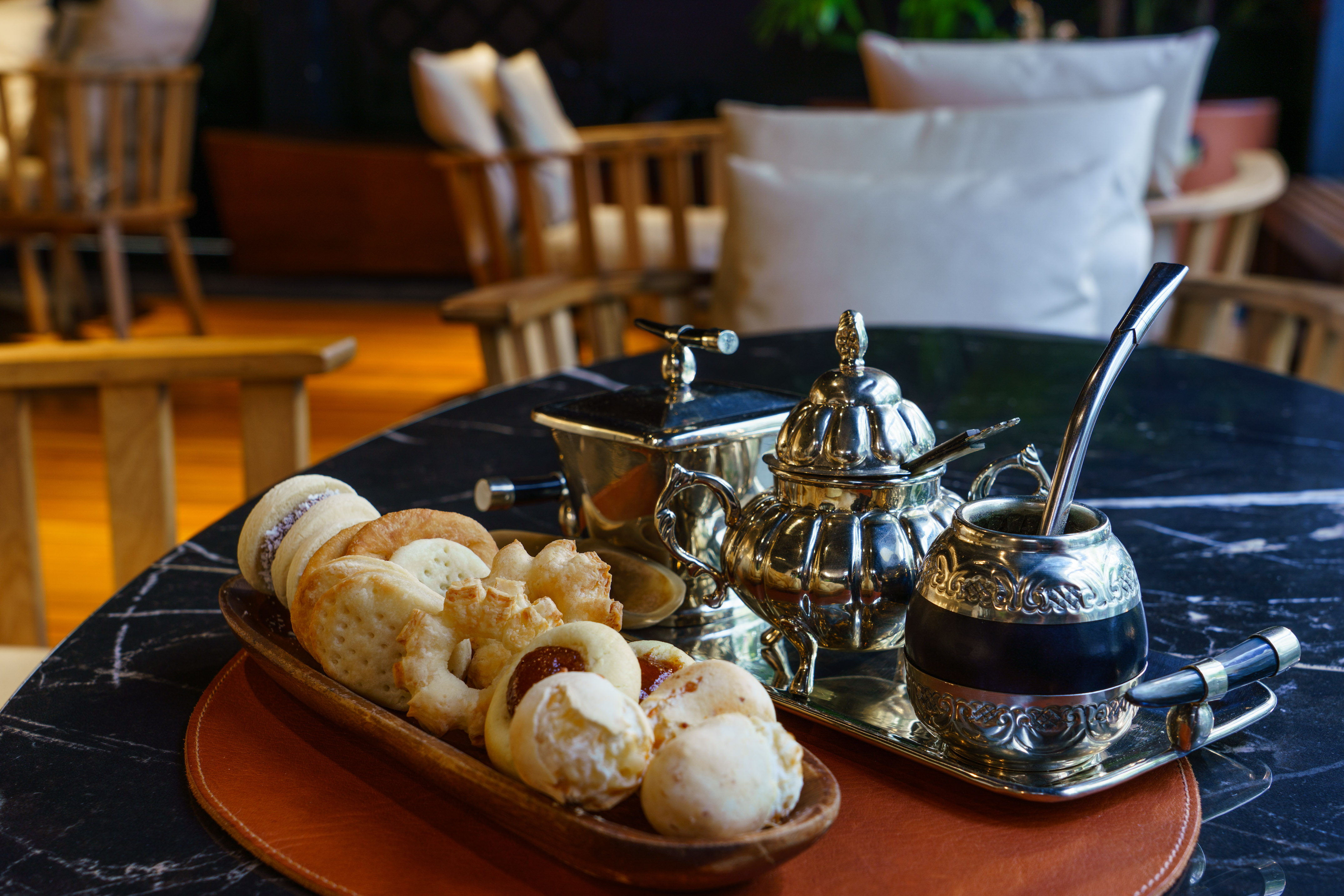 Mate tea, alfajores, and assorted pastries with silver service on a marble table.