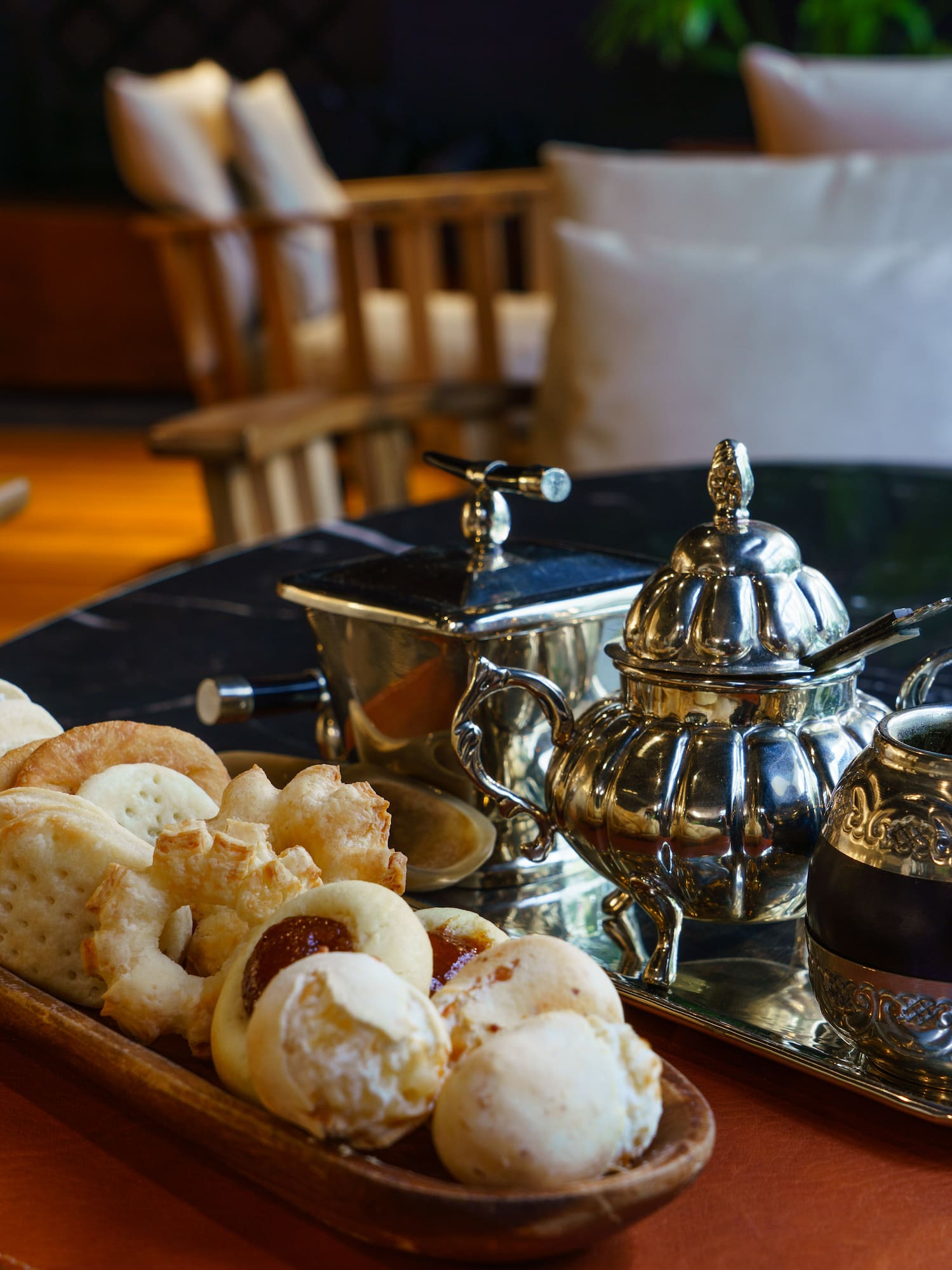 Mate tea, alfajores, and assorted pastries with silver service on a marble table.