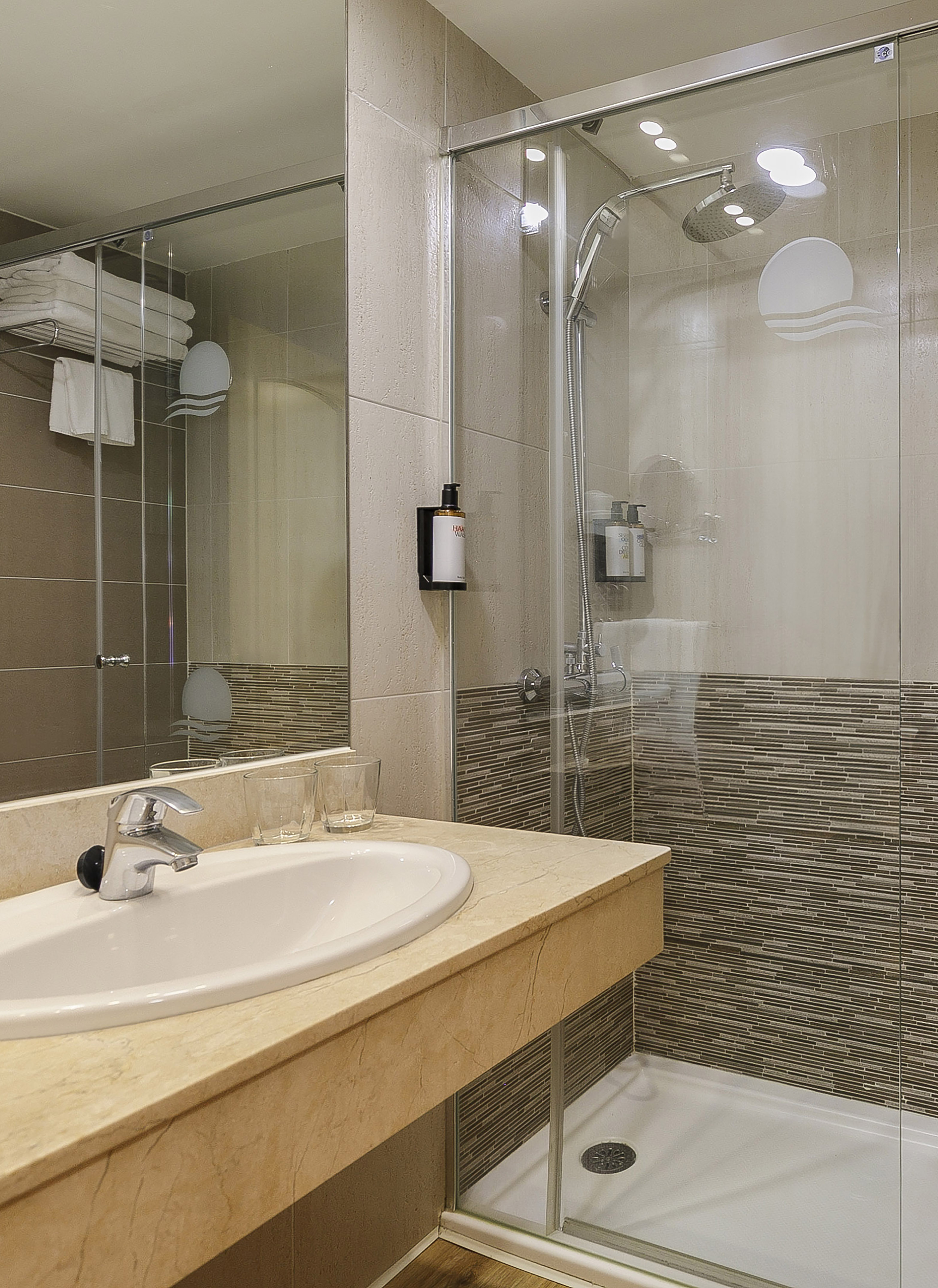 Modern bathroom with marble vanity, white sink, and glass shower.