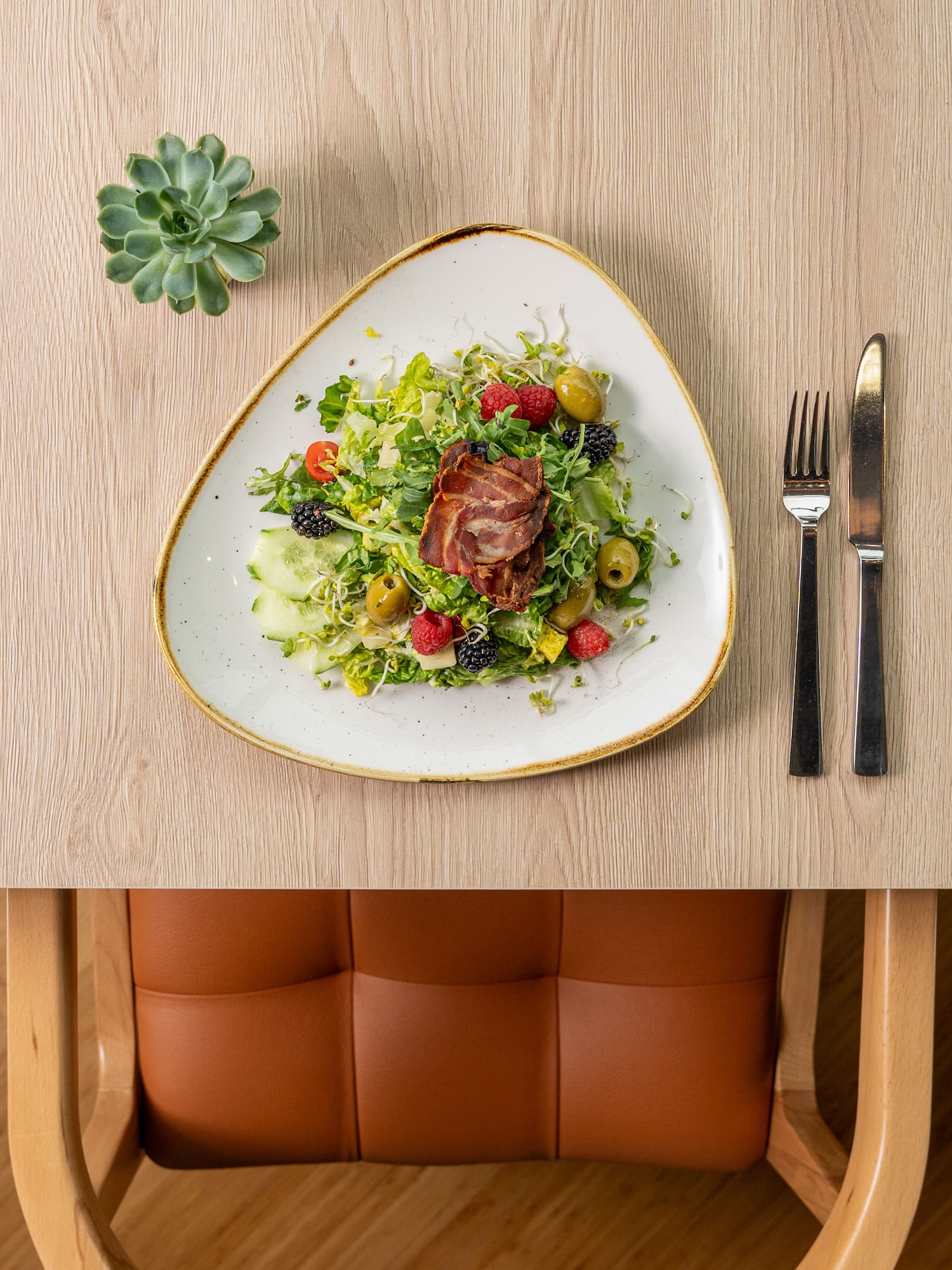 a plate of salad with fork and knife on a table
