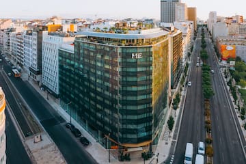 ME Lisbon hotel, modern glass building with rooftop terrace, city streets.