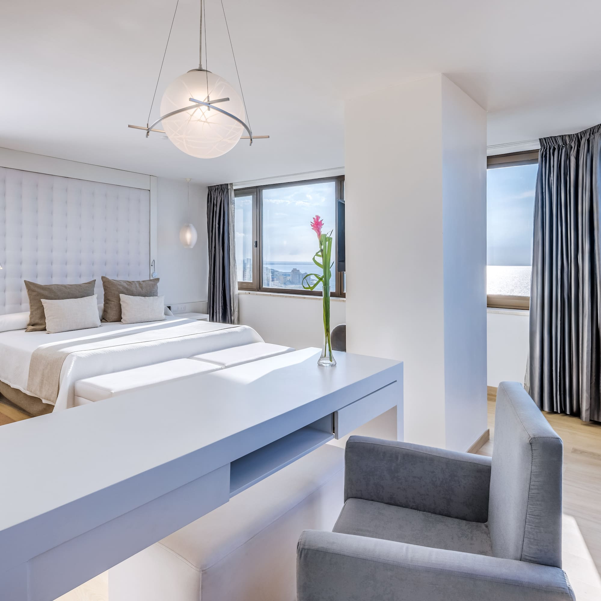 a room with two beds and a table with chairs and a flower in the vase