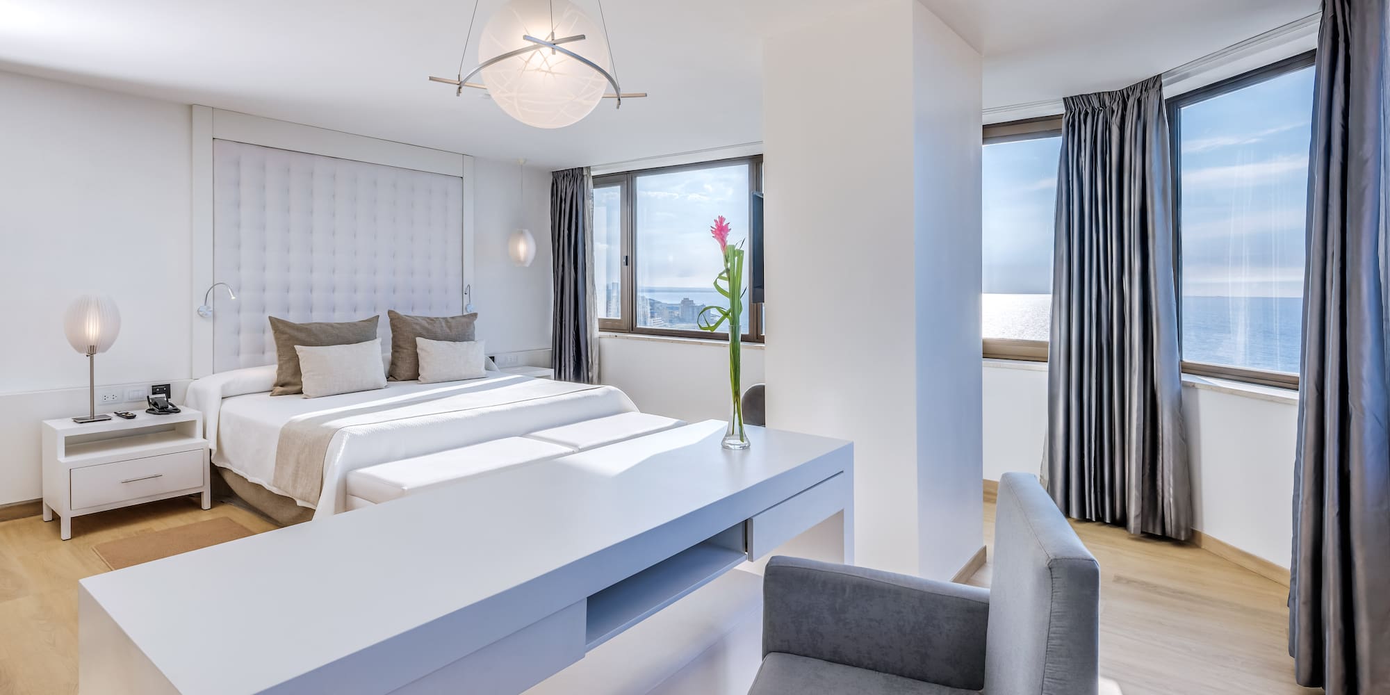 a room with two beds and a table with chairs and a flower in the vase