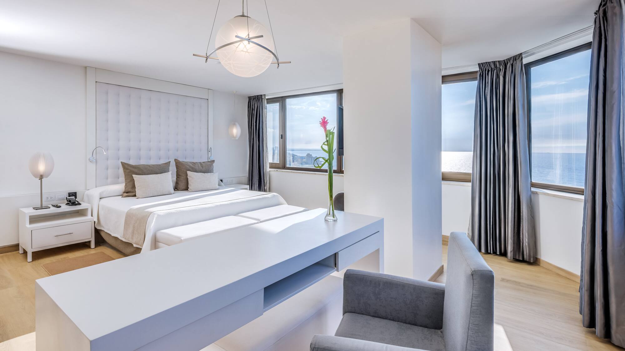 a room with two beds and a table with chairs and a flower in the vase