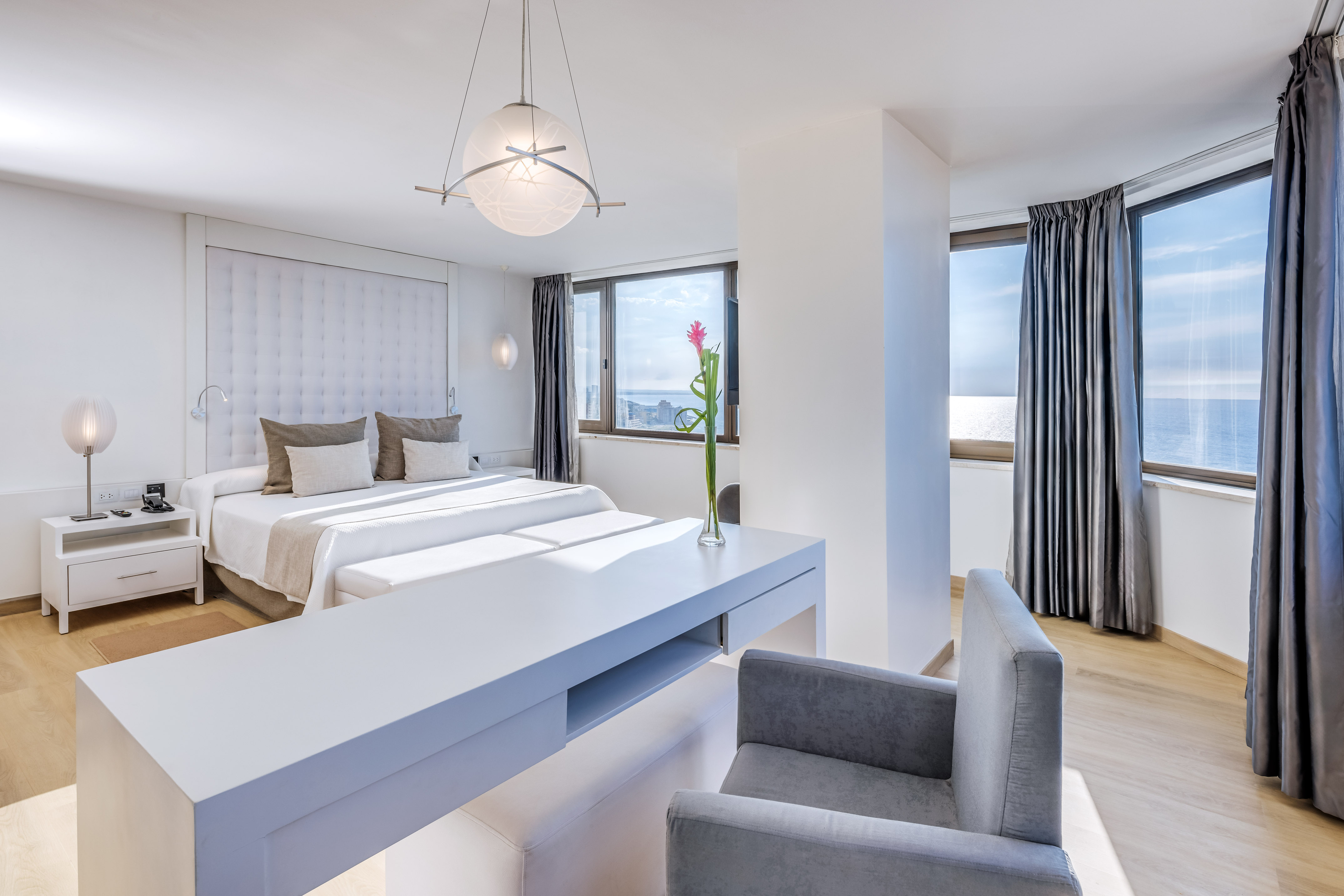 a room with two beds and a table with chairs and a flower in the vase