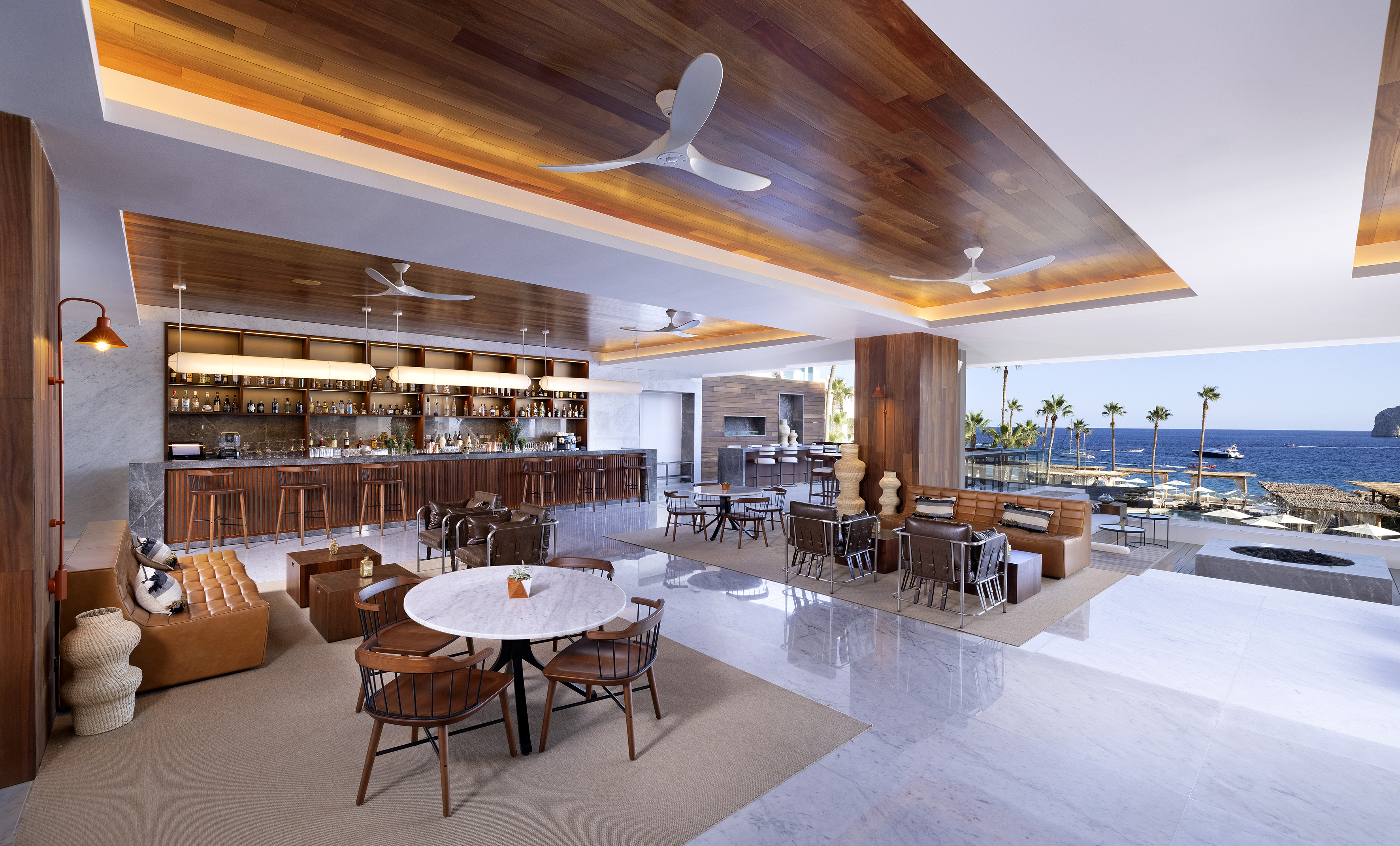 Luxury hotel bar and lounge with ocean view, modern wood and marble interior.