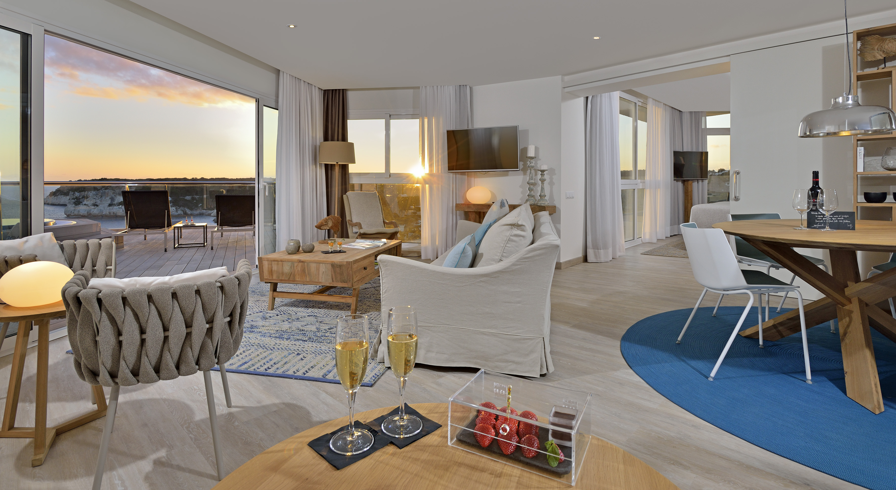 Oceanfront suite living room with sunset balcony view and dining area.