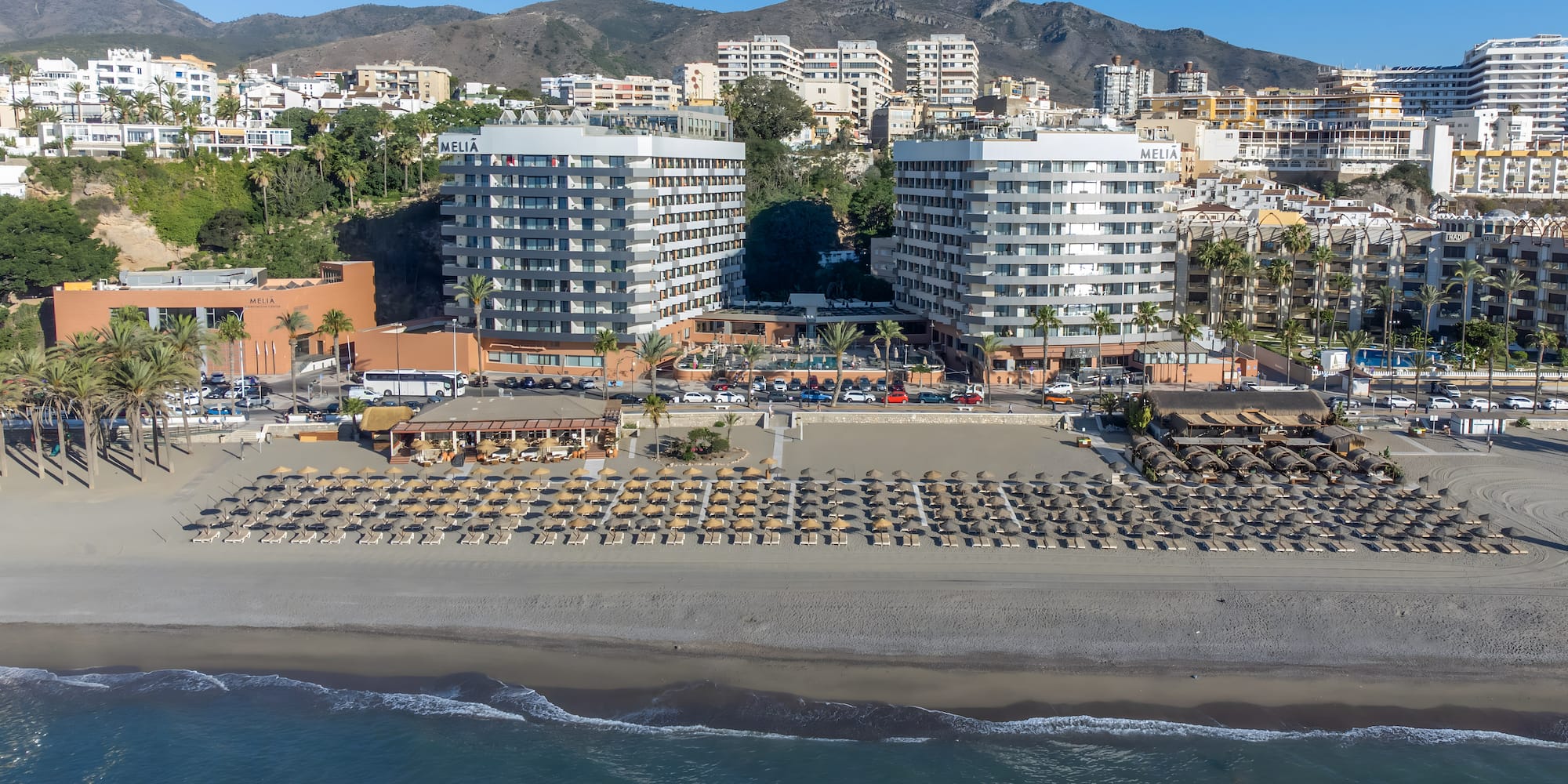 a beach with many buildings and a beach with many umbrellas