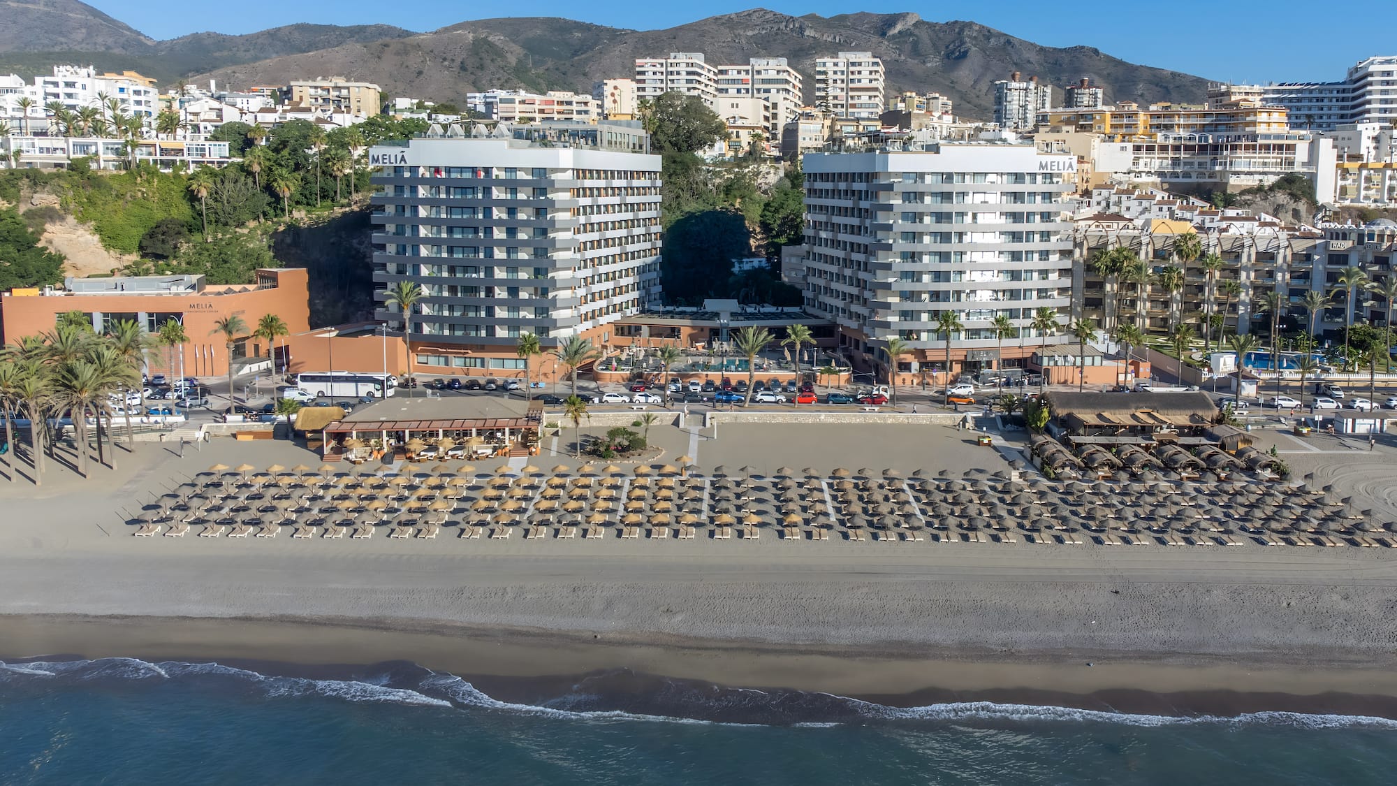 a beach with many buildings and a beach with many umbrellas