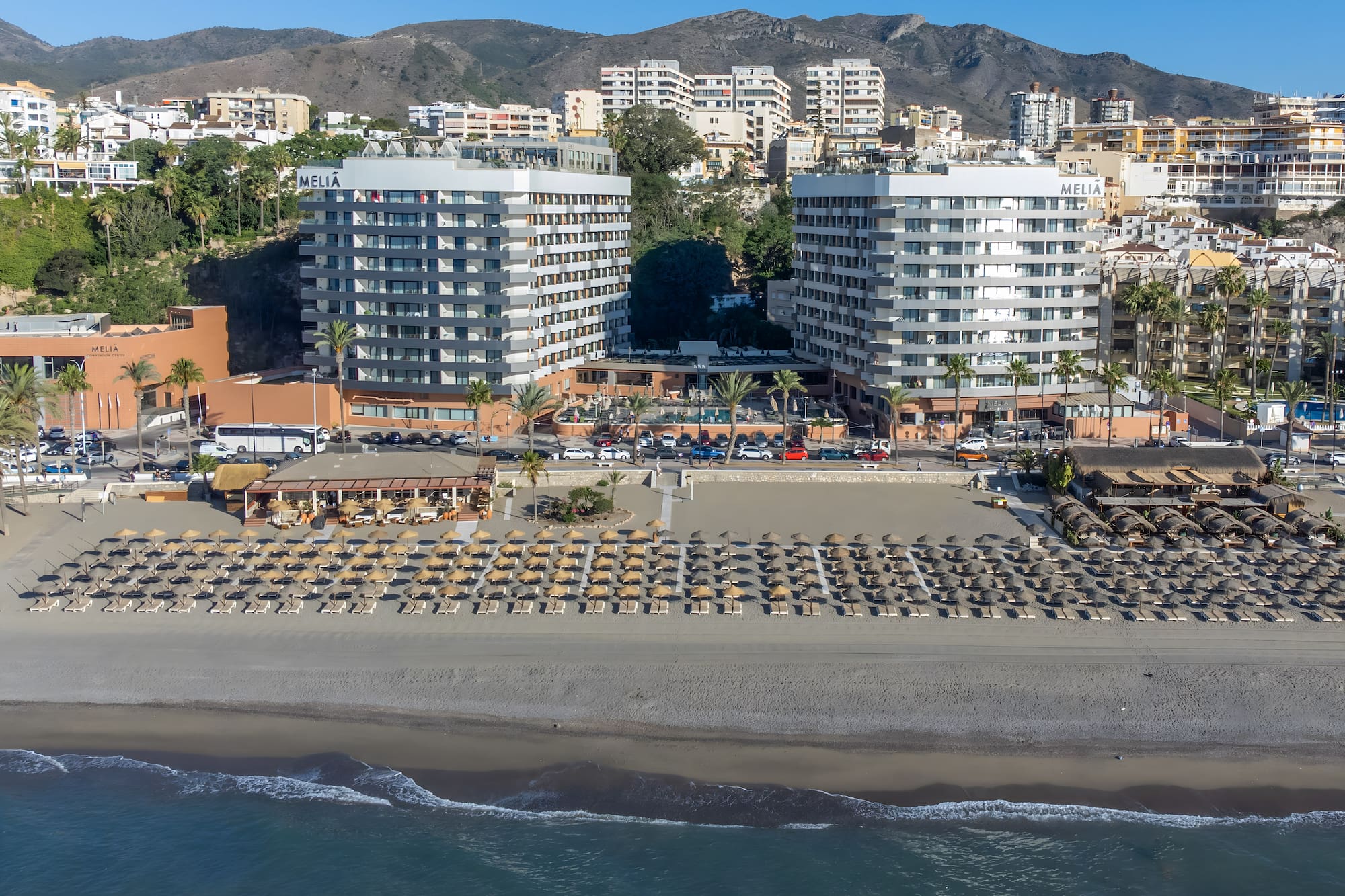 a beach with many buildings and a beach with many umbrellas