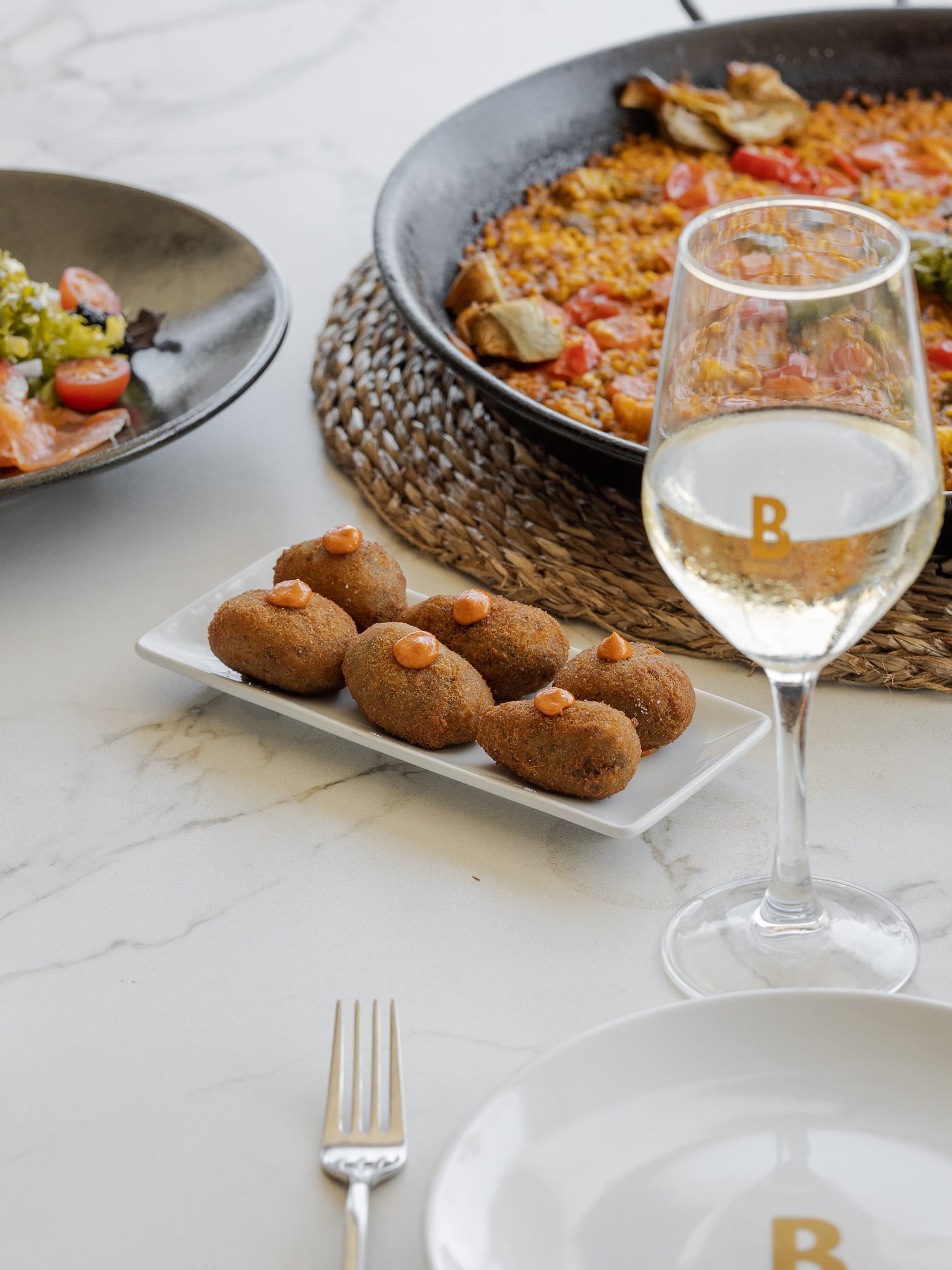 food on a plate next to a glass of wine