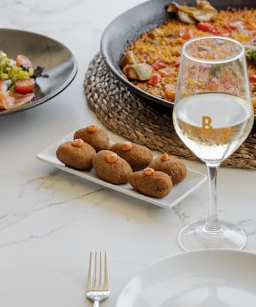 food on a plate next to a glass of wine