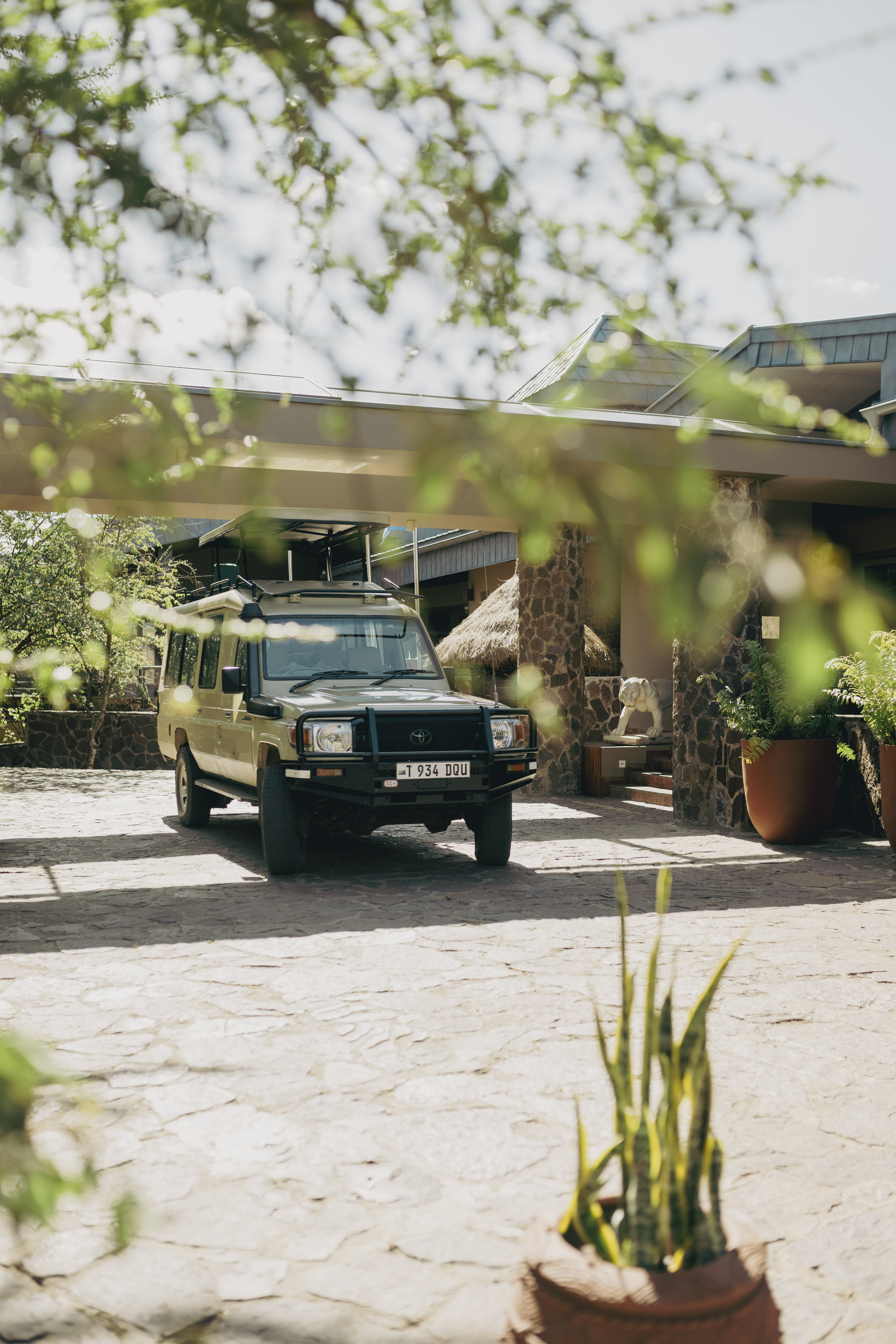 Safari vehicle parked at a luxury African lodge entrance.