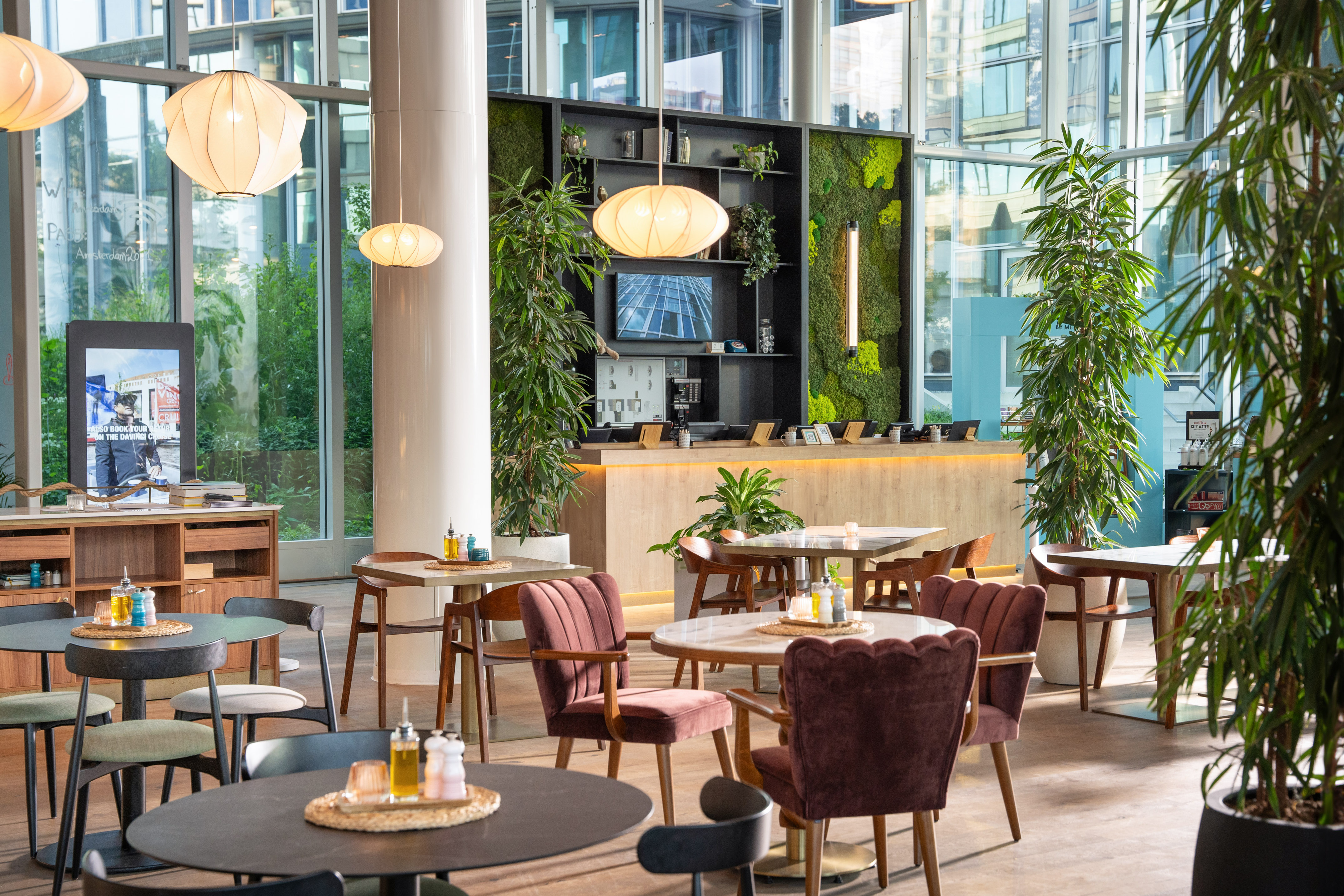 Stylish modern cafe with biophilic design, velvet chairs, and a living wall.