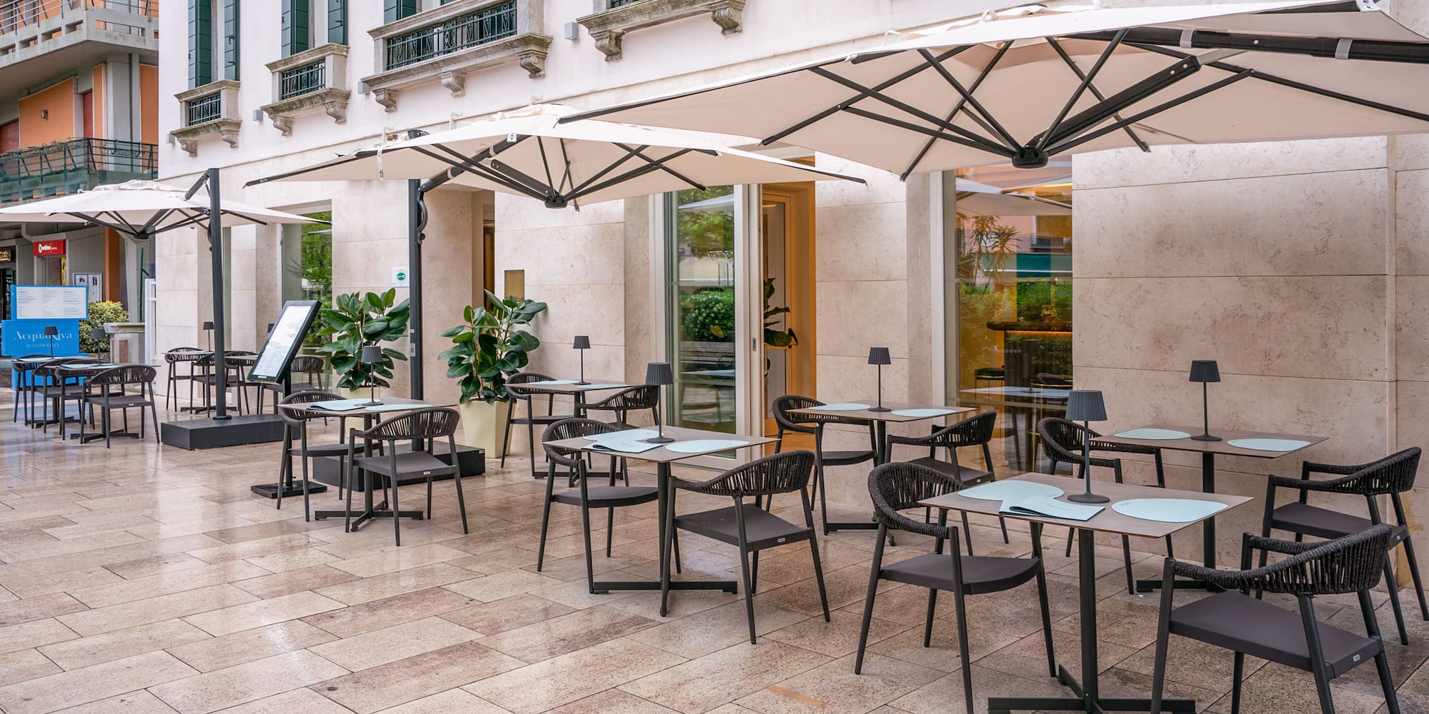 Modern outdoor restaurant patio with shaded seating, tables, and umbrellas.