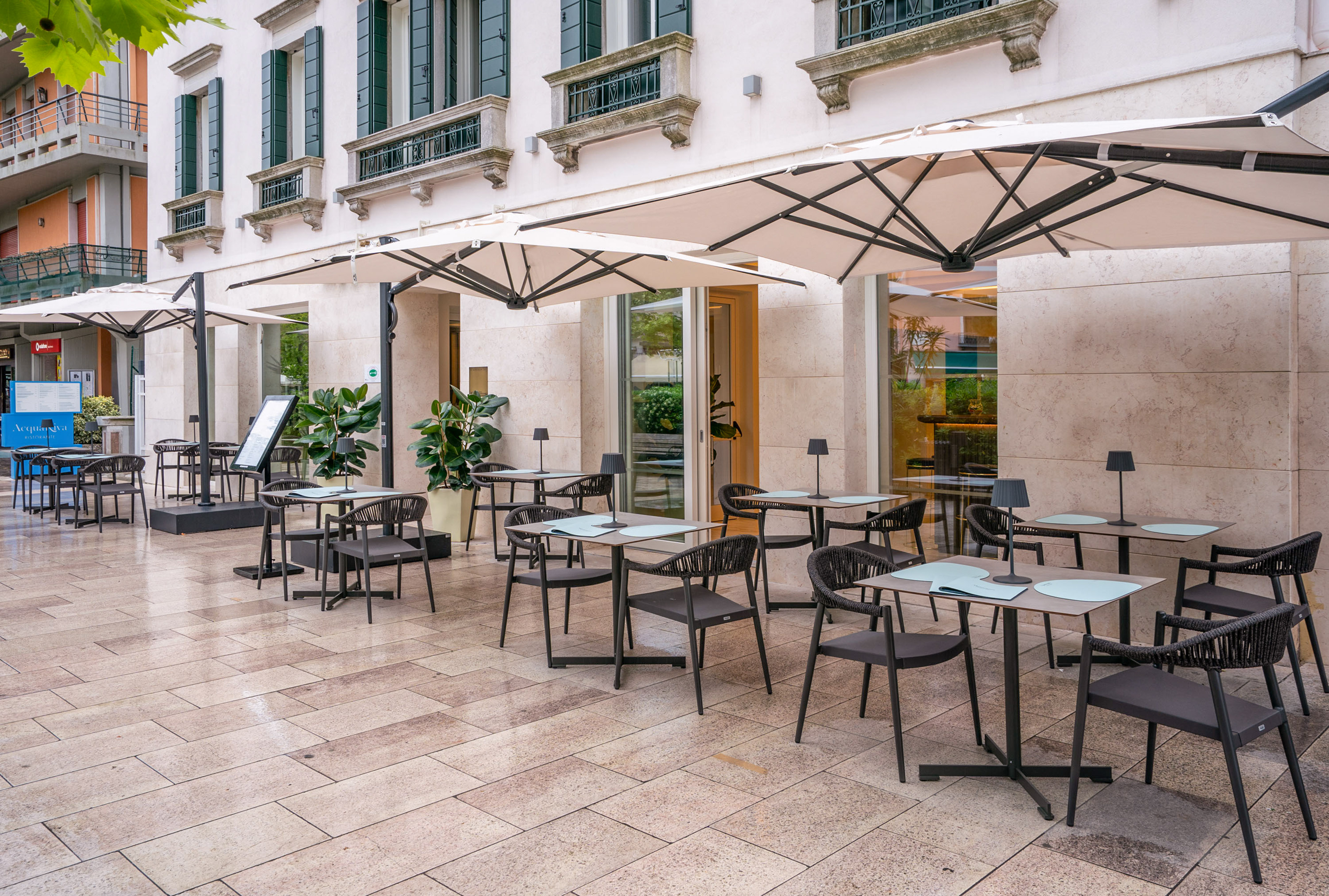 Modern outdoor restaurant patio with shaded seating, tables, and umbrellas.