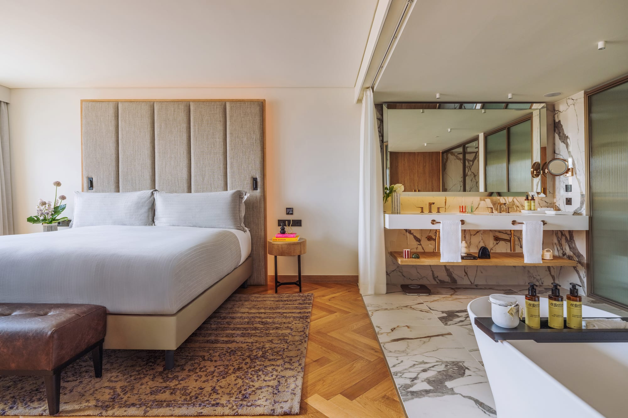 Luxury hotel suite with modern bedroom, king bed, and open marble bathroom.