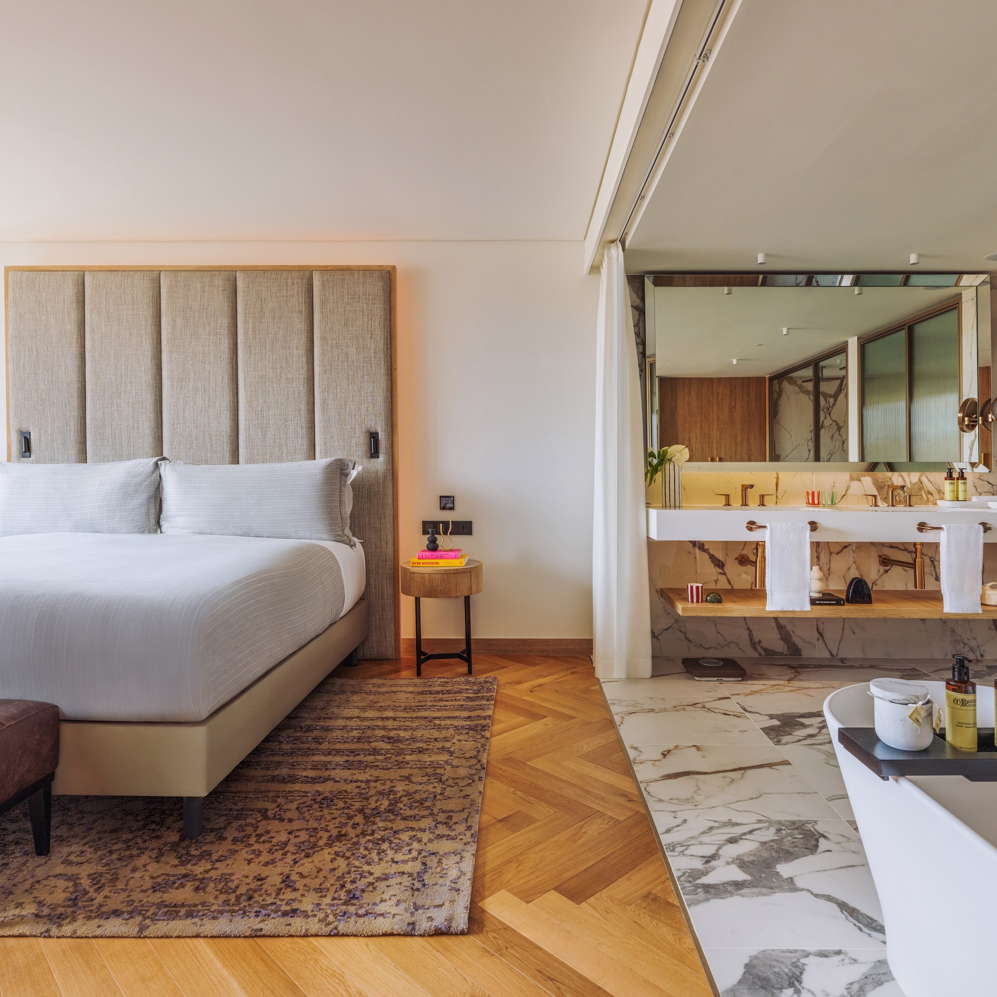 Luxury hotel suite with modern bedroom, king bed, and open marble bathroom.