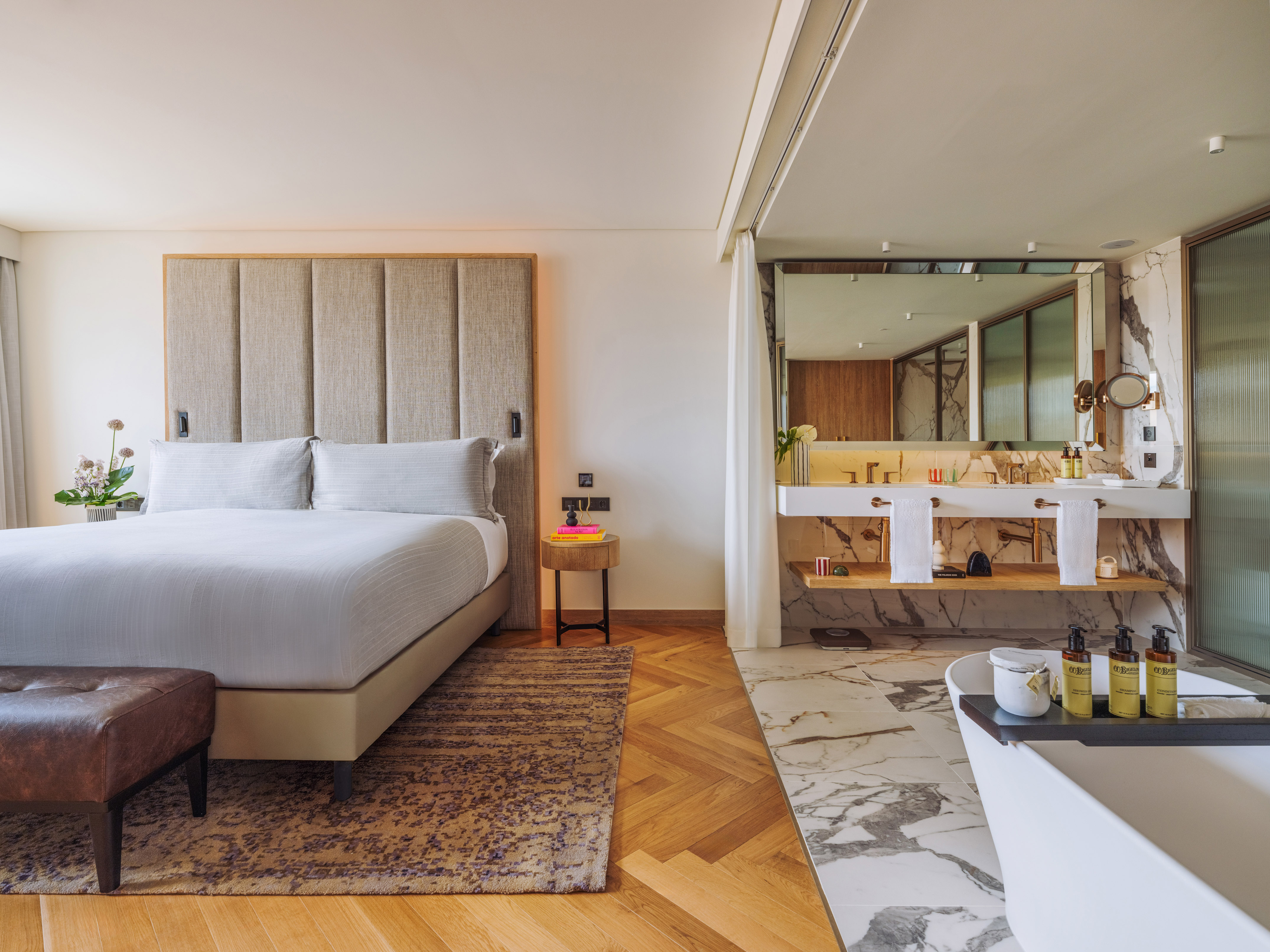 Luxury hotel suite with modern bedroom, king bed, and open marble bathroom.