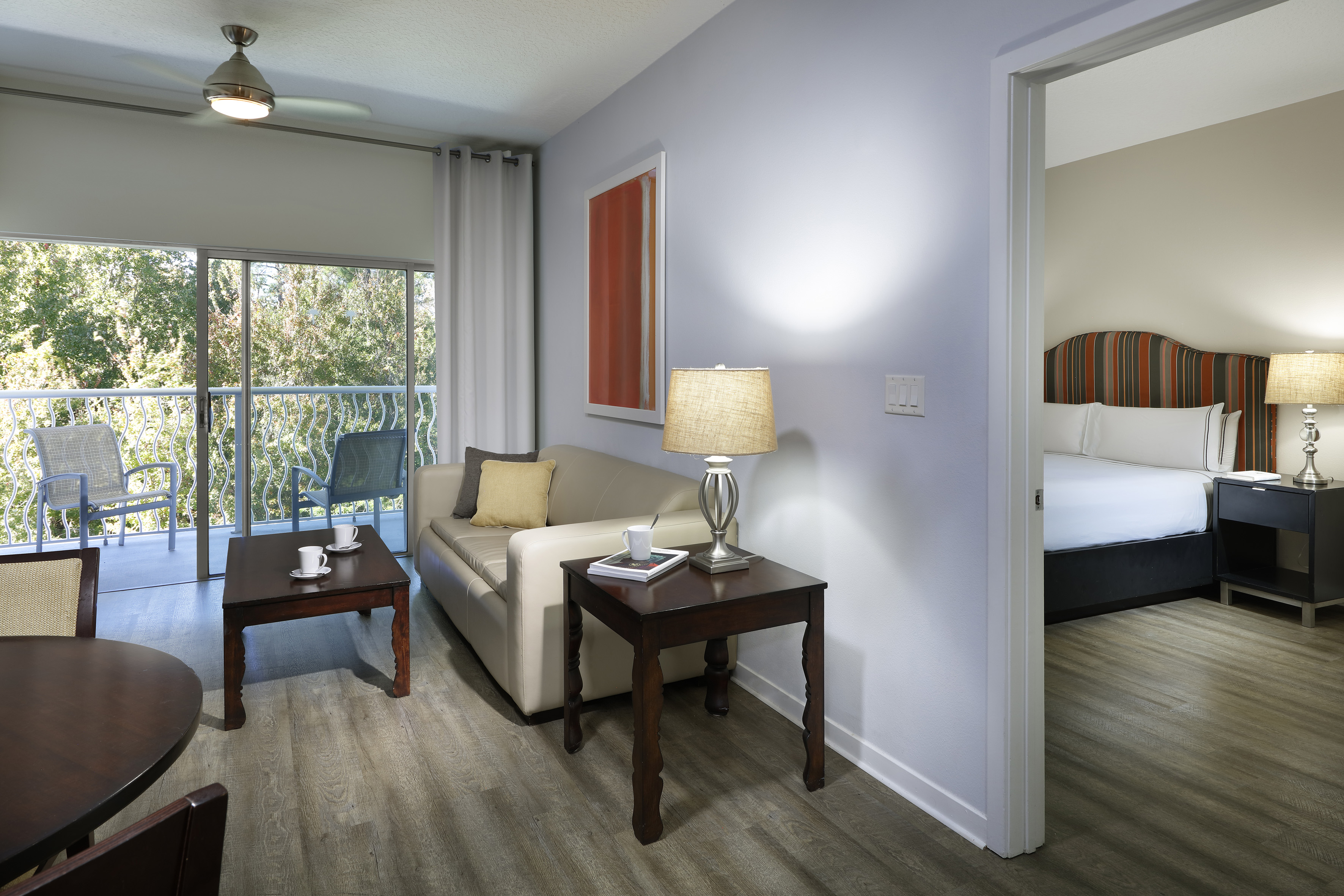 Modern hotel suite living room, balcony, sofa, and connected bedroom.